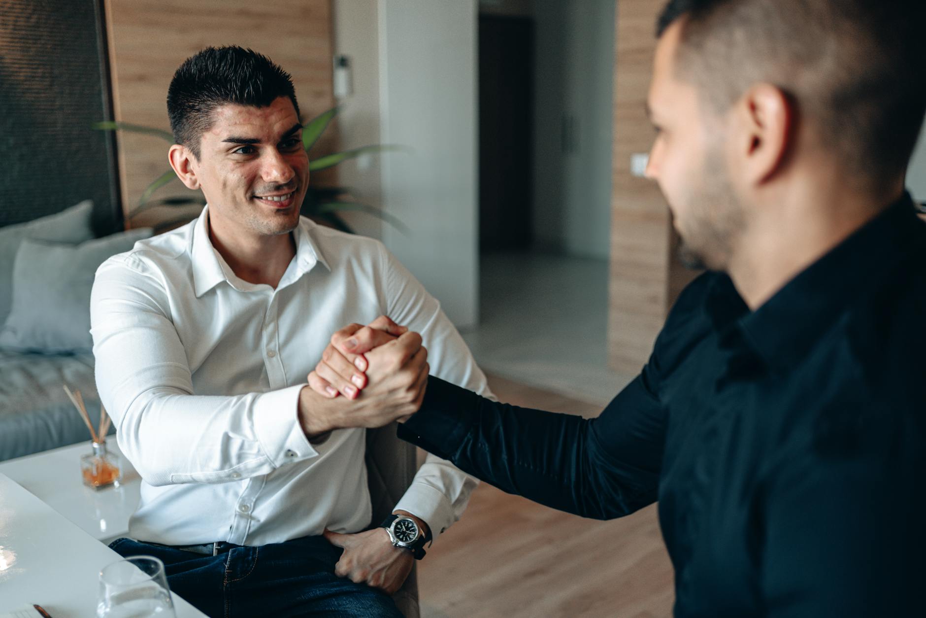 Two businessmen shaking hands in a modern office setting, sealing a successful deal. - build trust relationship