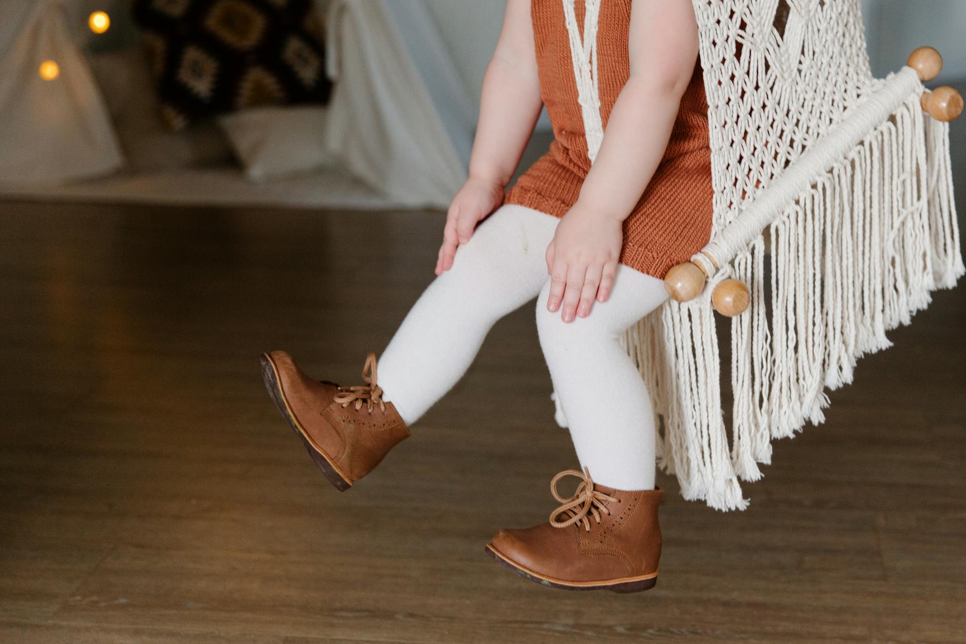 Child sitting comfortably on a macrame swing indoors, wearing a casual outfit. - child allergy mood swings