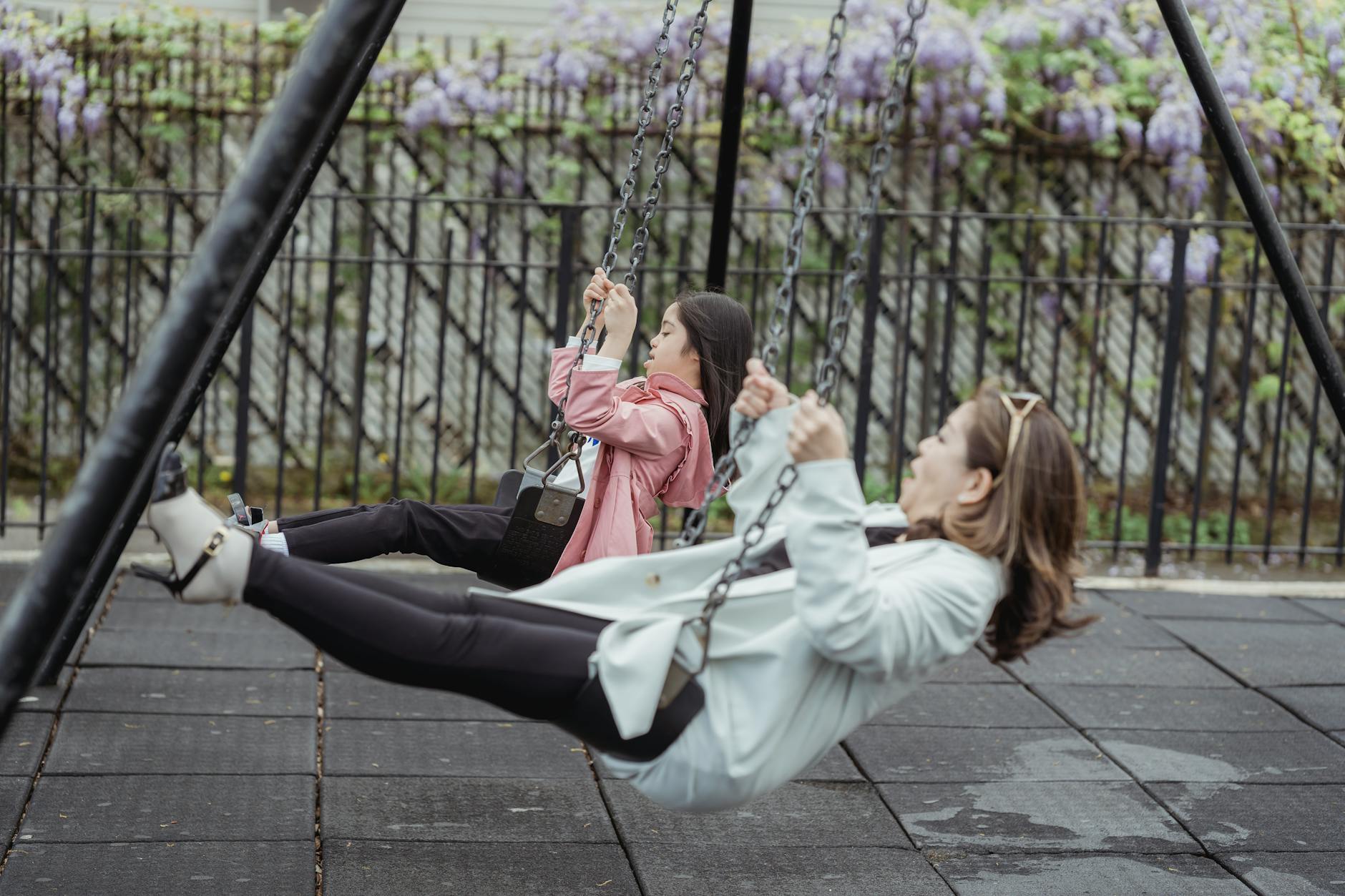 Asian mother and daughter spending quality time swinging in a playground. - child allergy mood swings