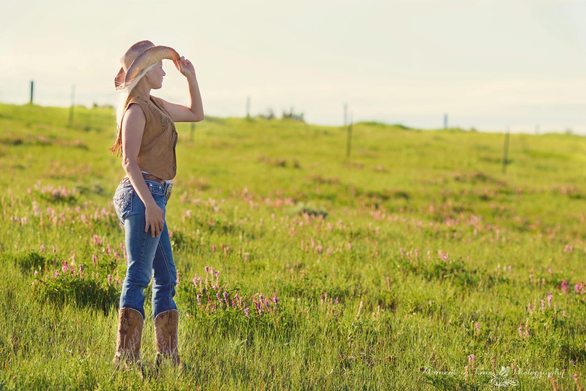 A woman wearing a cowboy hat stands in a sunlit countryside field. - childhood meltdowns