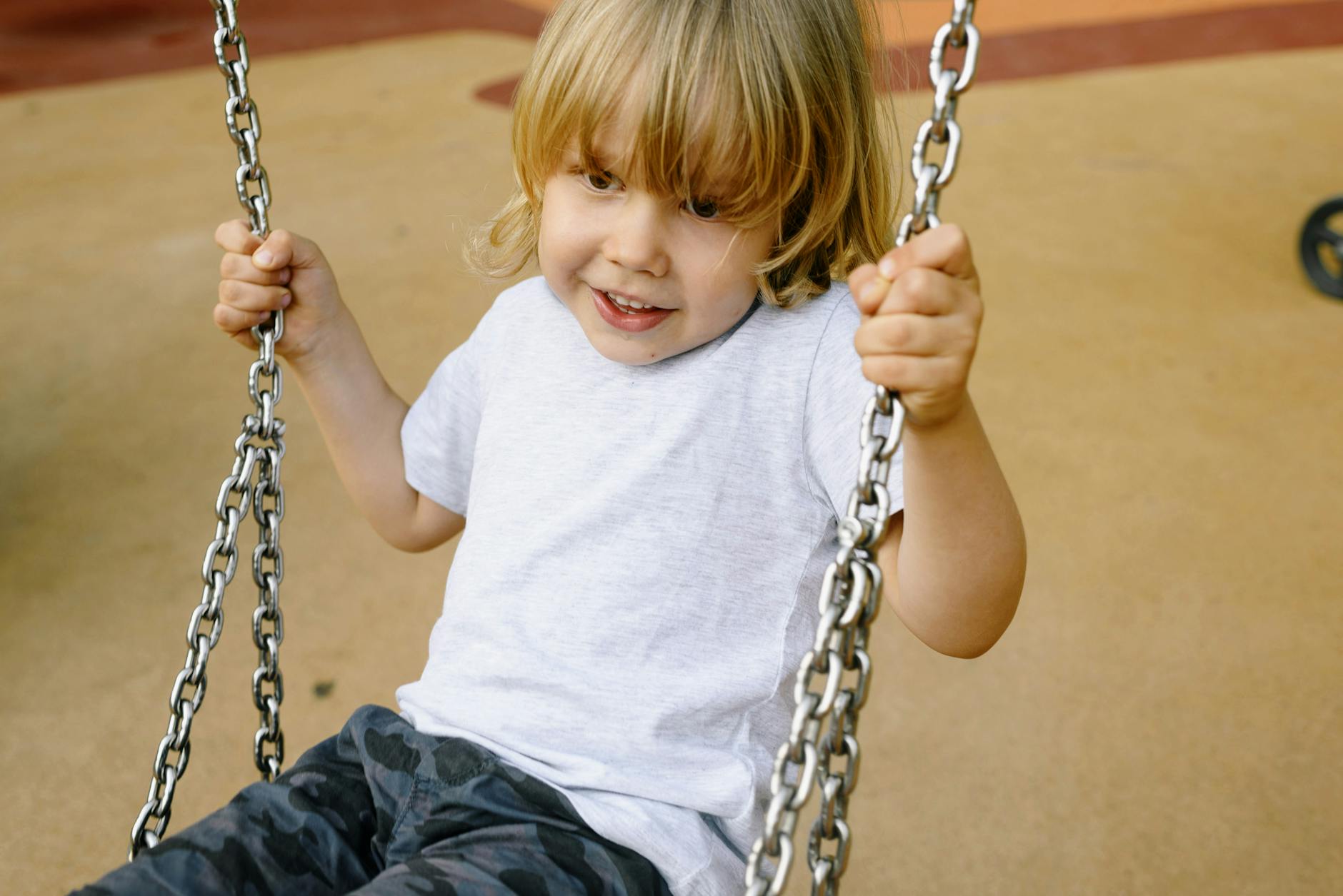 Smiling child enjoying a swing ride at an outdoor playground. - childhood meltdowns