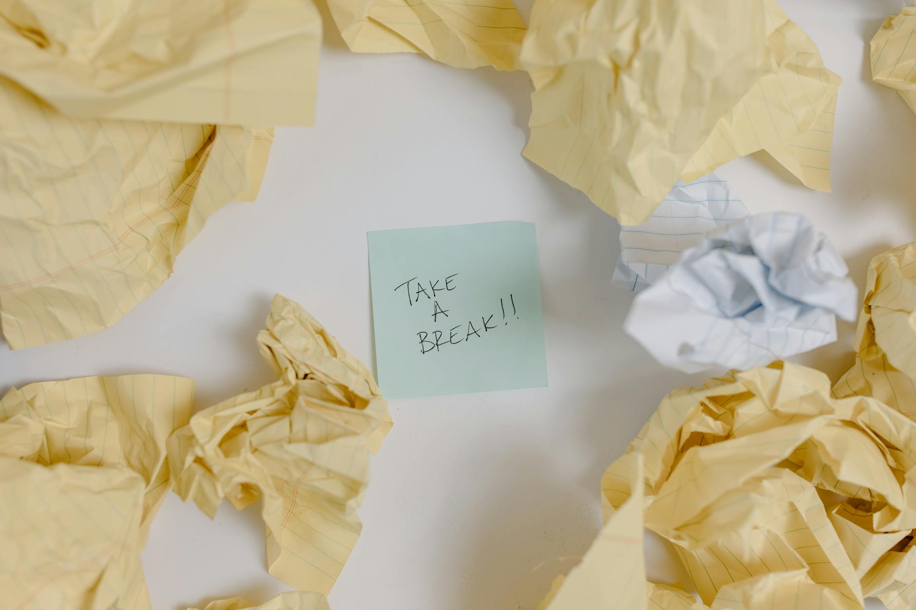 A top view of crumpled papers surrounding a sticky note with 'Take a Break'. - clear mental clutter