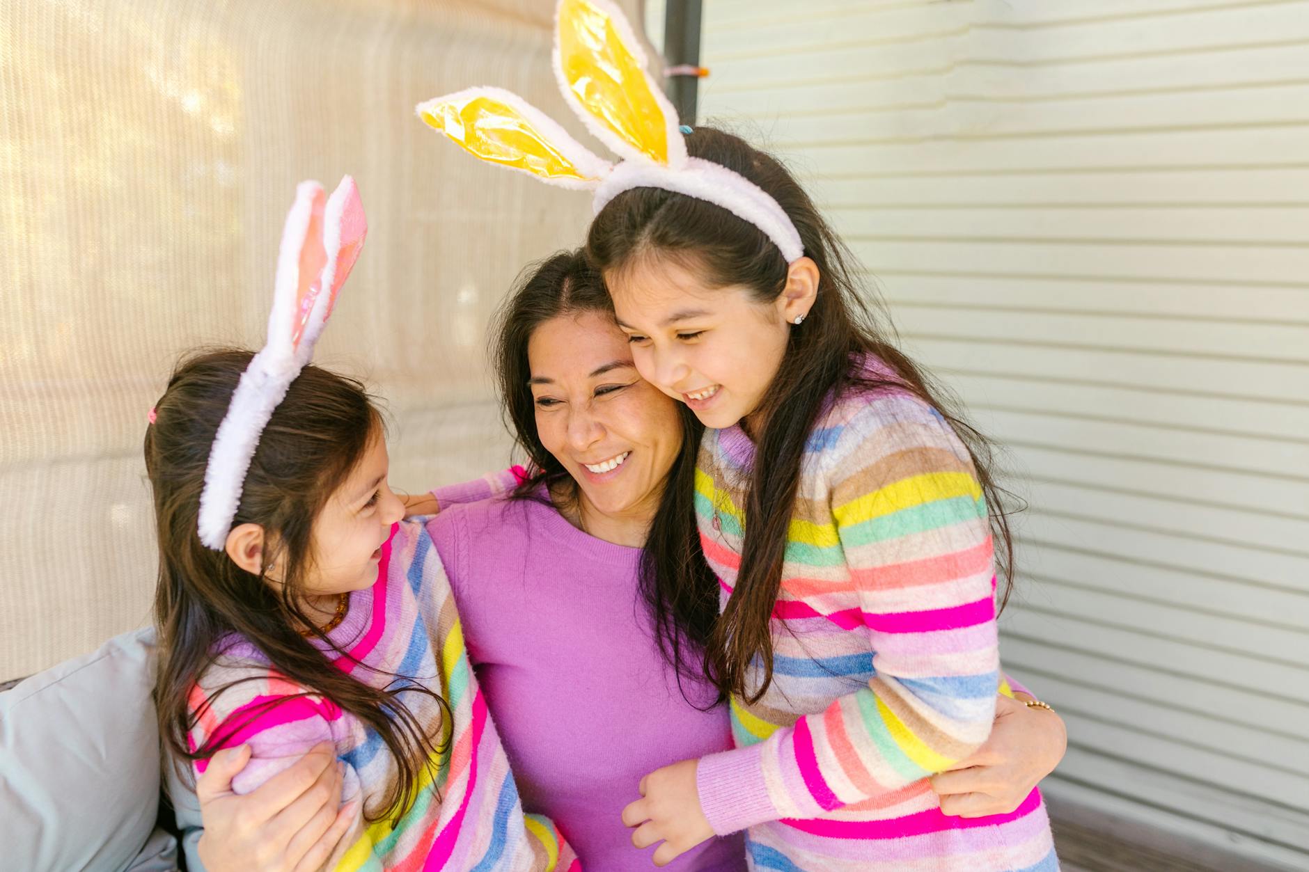Joyful family moment with mother and daughters wearing bunny ears for Easter celebration. - co-parenting spring break