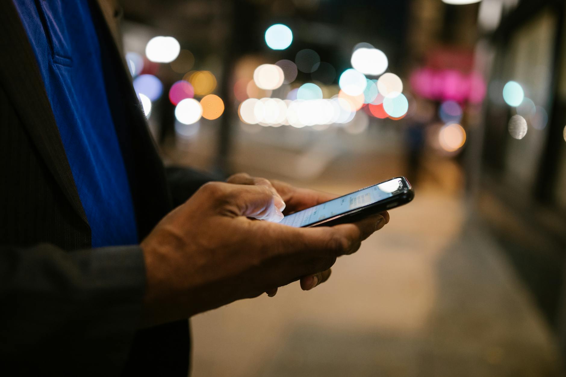 Close-up of a man using a smartphone on a busy city street at night. - couple communication goals
