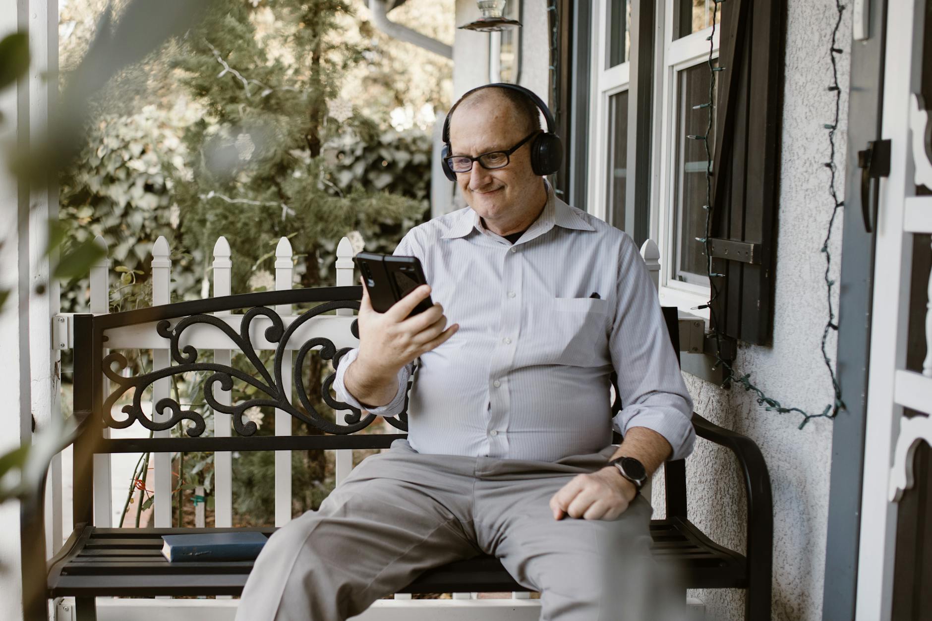 Senior man on porch engaging in a video call using a smartphone, relaxed setting. - couple communication goals
