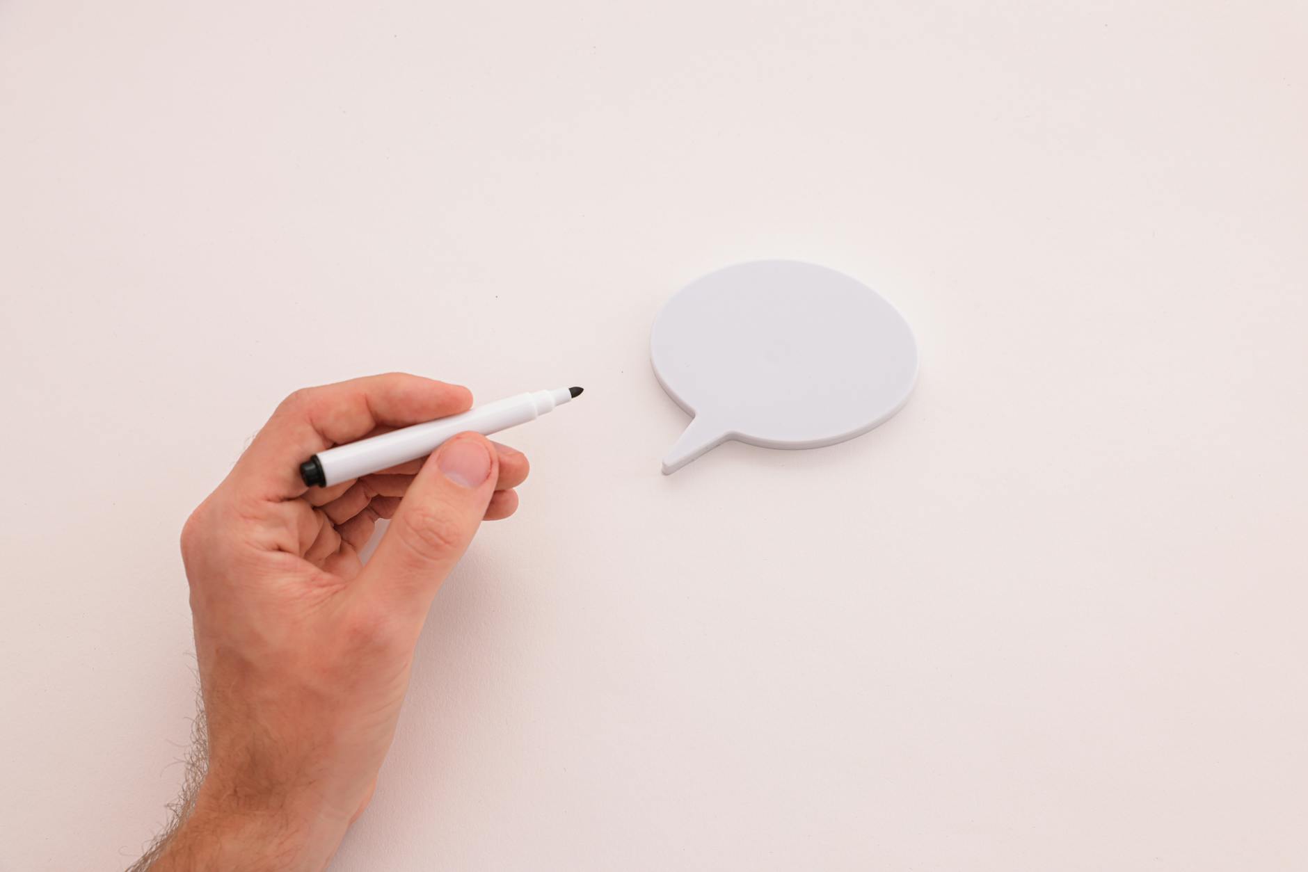 A hand holding a marker next to a blank speech bubble on a white background offers space for text or illustrations. - couple communication tips
