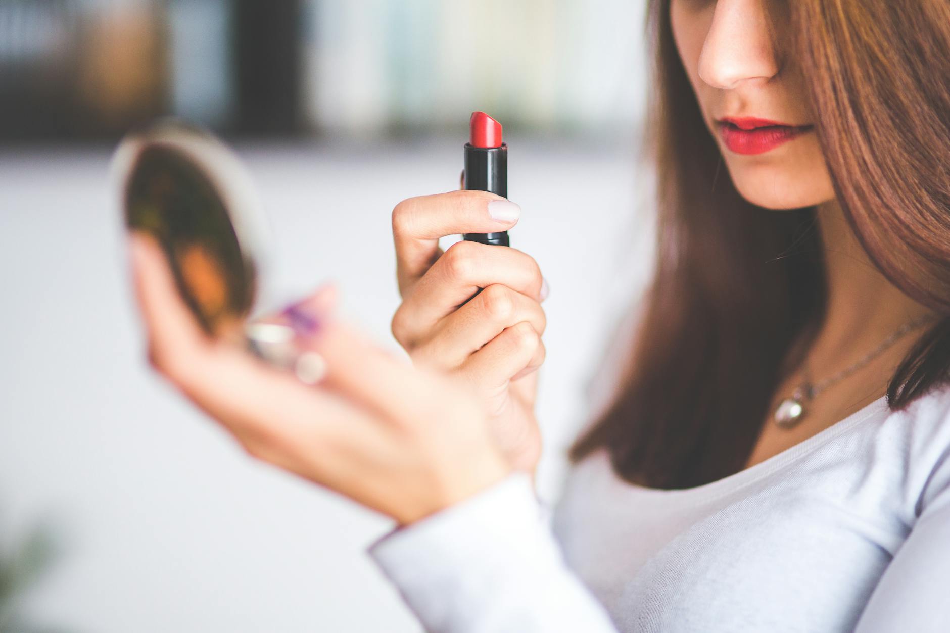 Close-up of woman applying red lipstick while holding a compact mirror. - couple communication tips