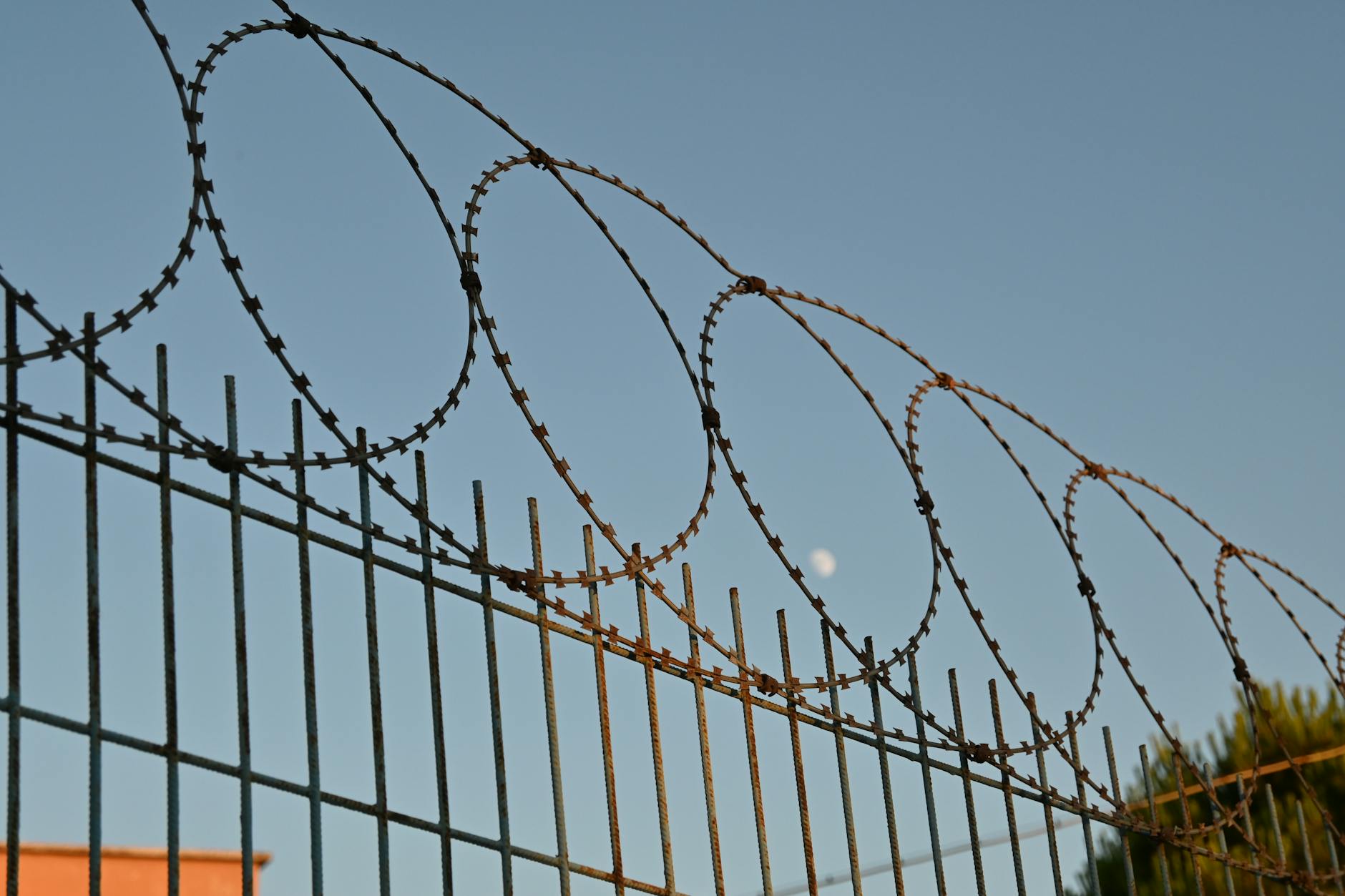 A close-up view of a barbed wire fence under a clear blue sky, suggesting protection and security. - couple energy boundaries
