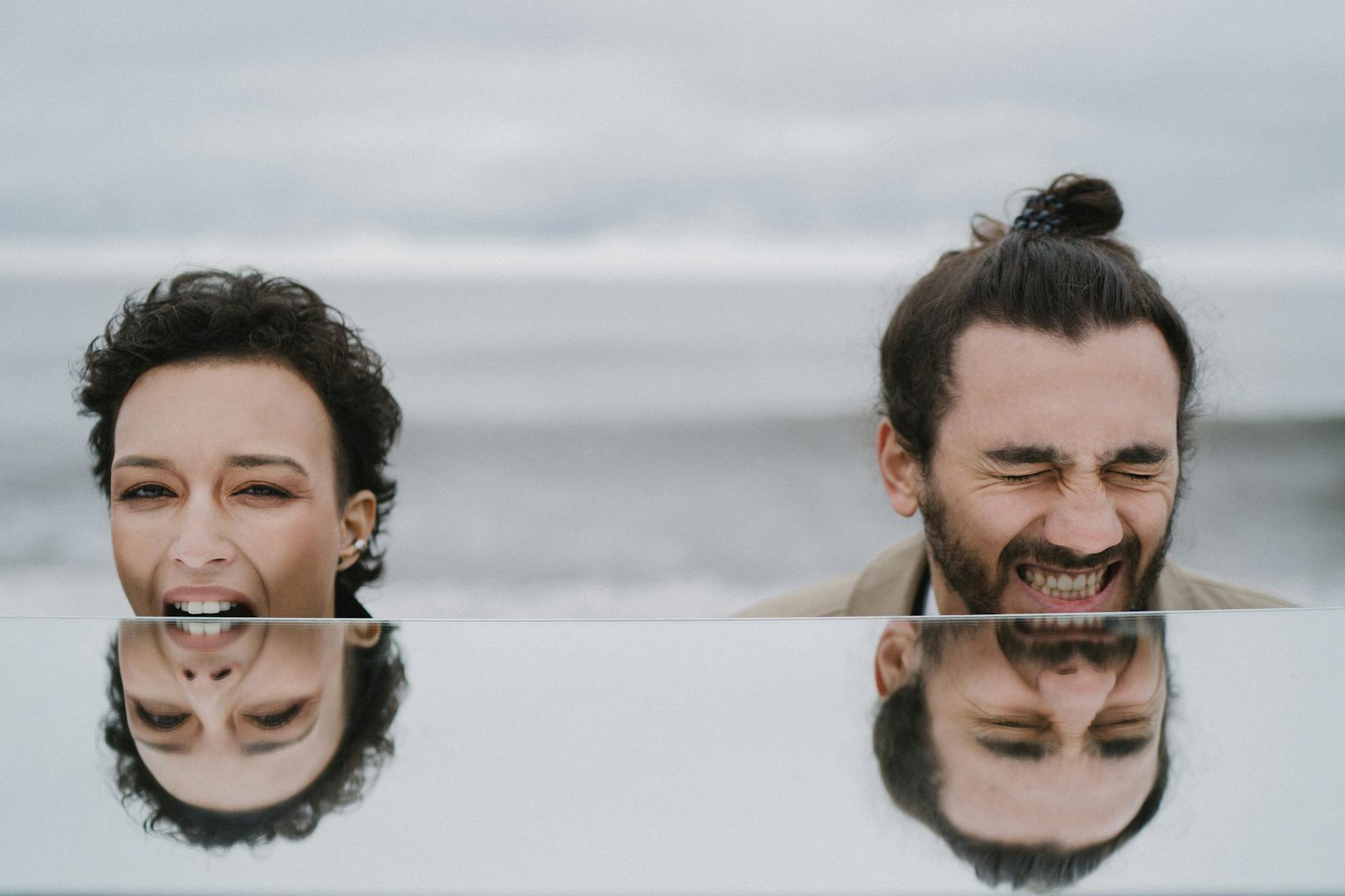 A joyful couple shares a laugh at the beach, captured with their reflection. - couple resentment spring