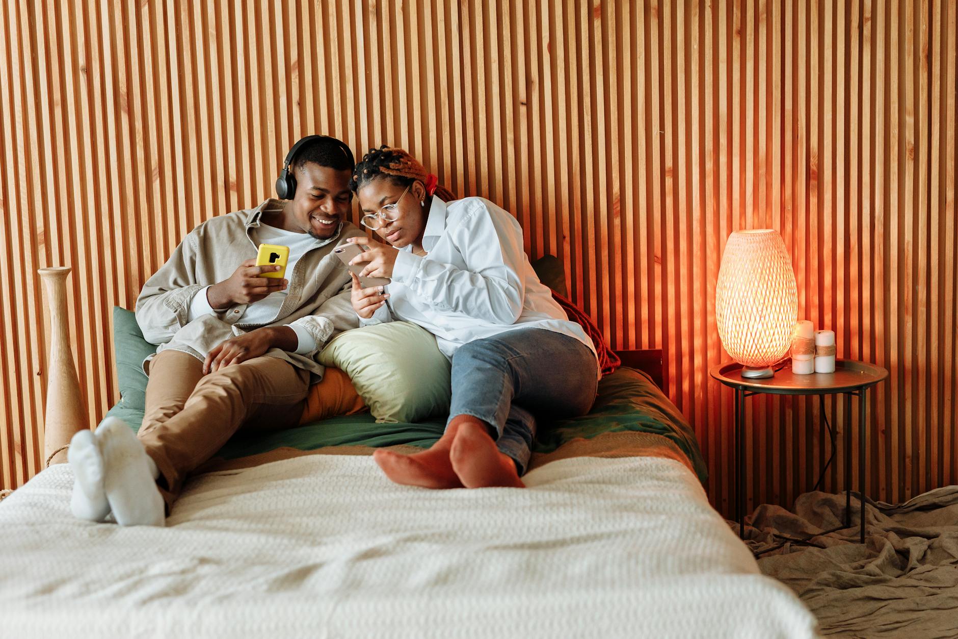 Couple enjoying a cozy moment with smartphones in a modern bedroom setting. - couples communication needs