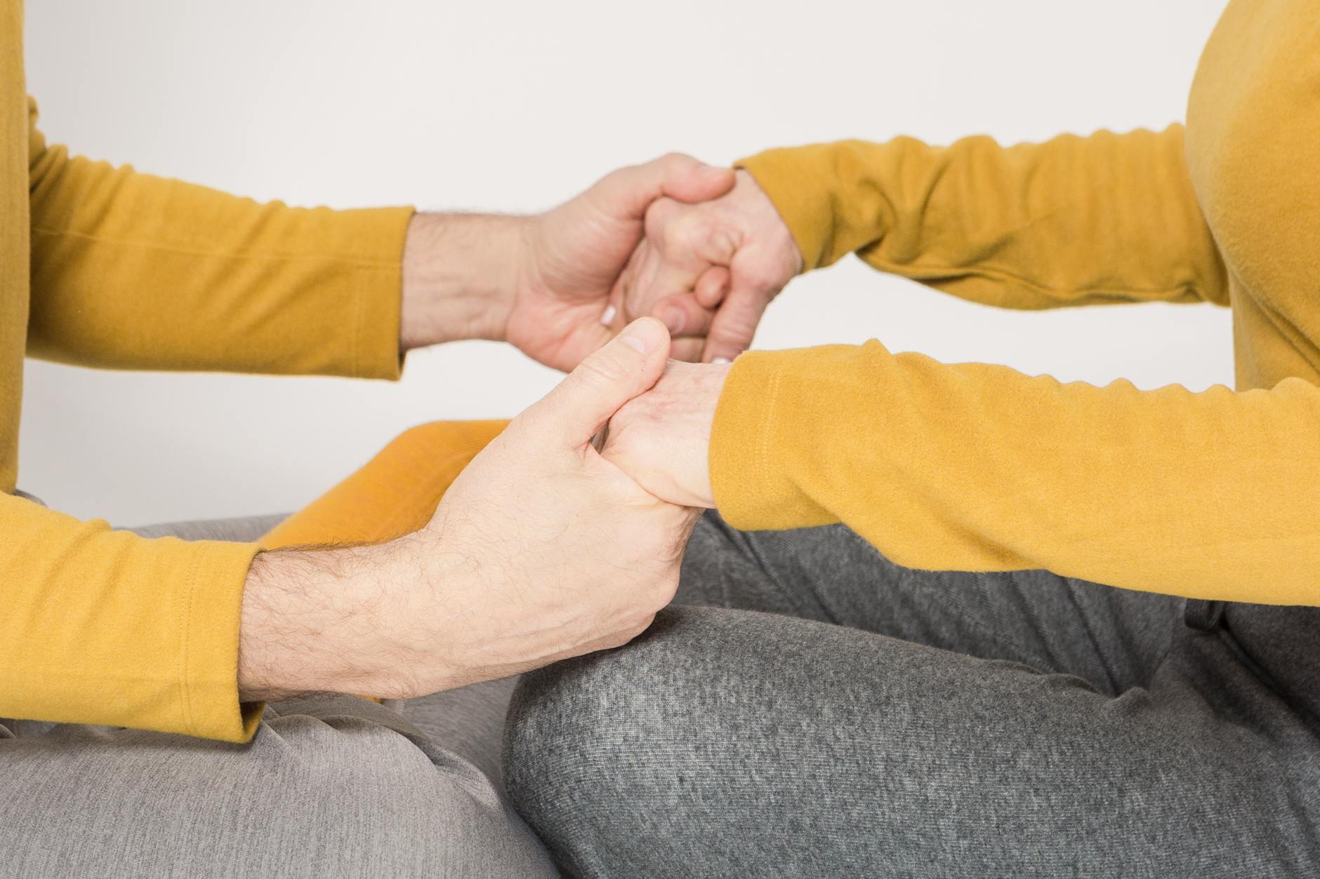 A close-up of two adults holding hands in a gesture of support and love. - couples communication needs