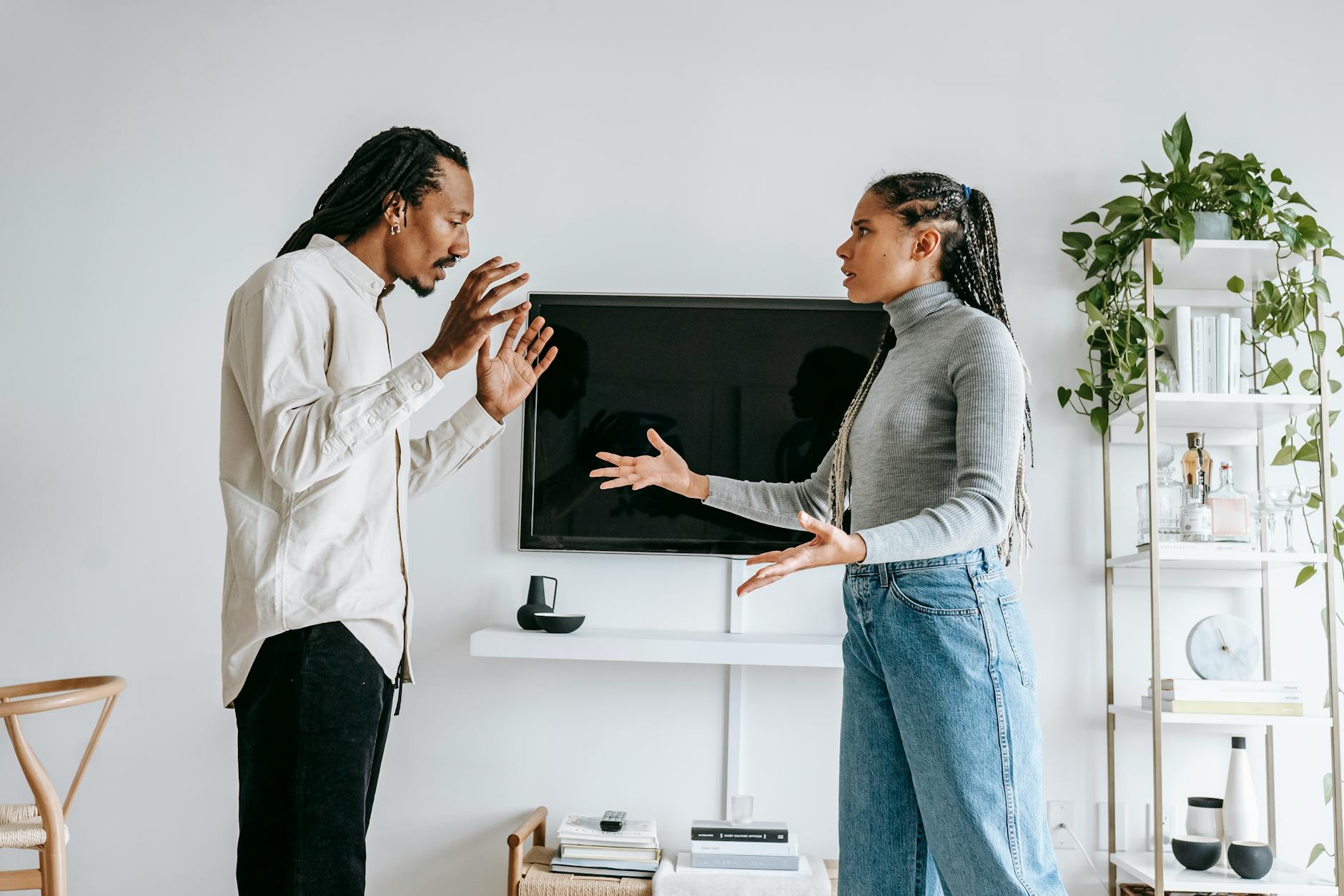 A young couple engaged in a tense argument in their modern living room setting. - couples communication needs