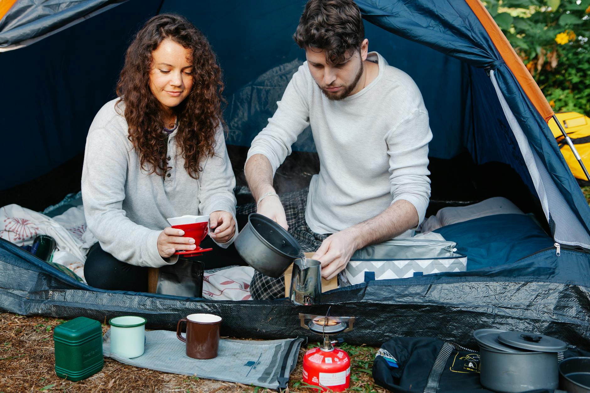 A couple making coffee at a campsite in a tent, enjoying the outdoors and each other's company. - couples spring reconnection