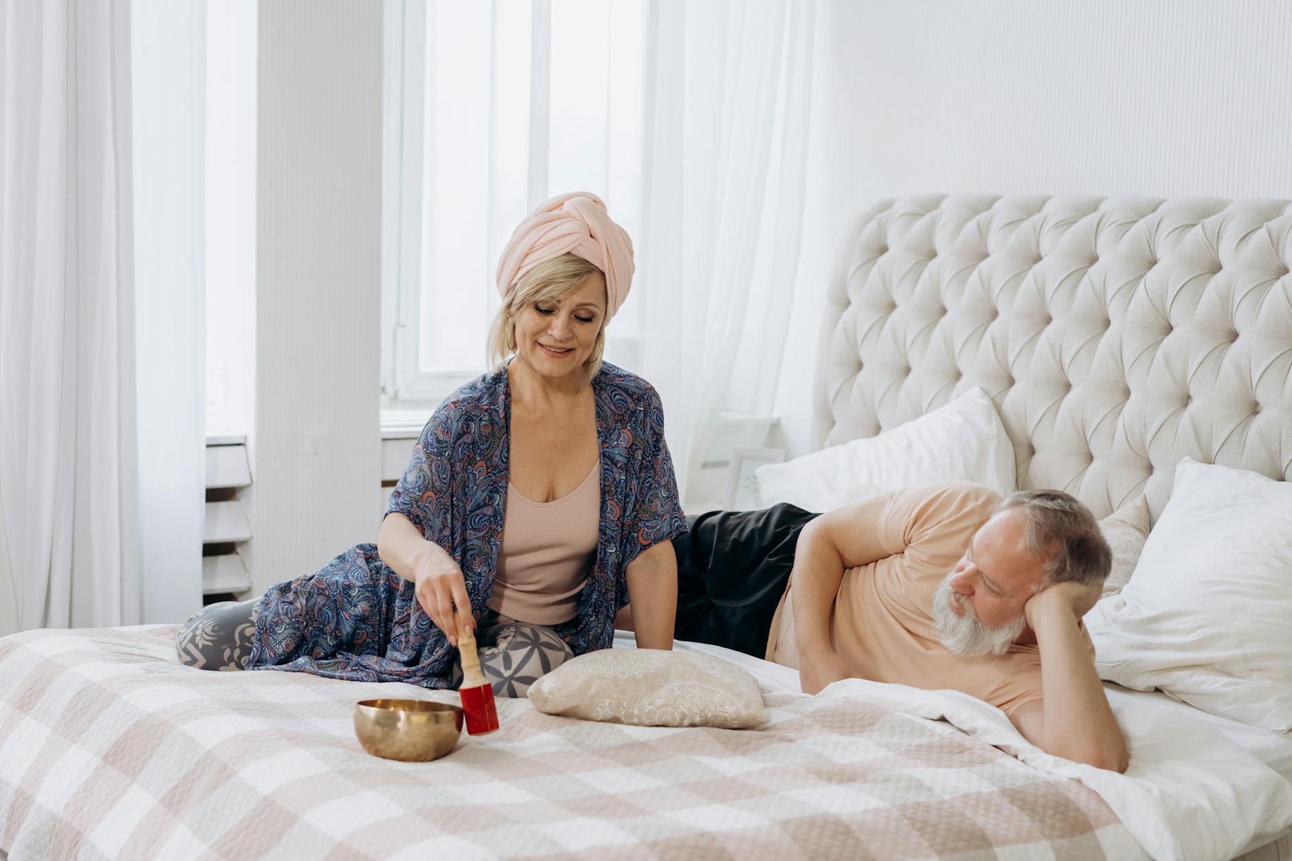 A couple enjoying relaxation with a Tibetan singing bowl in a bright bedroom. - couples therapy february