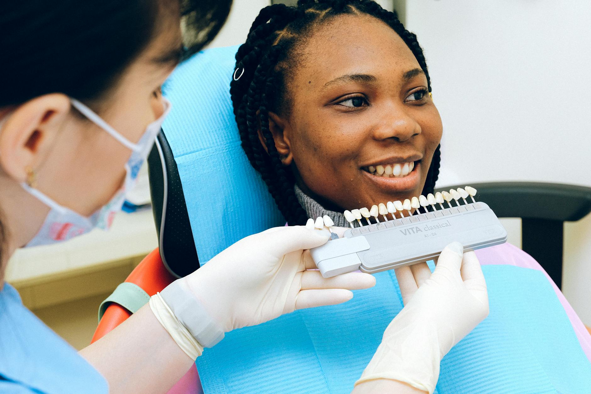 Cheerful black woman sitting in dental chair of modern dentist office and checking teeth implant while looking away - couples therapy guide