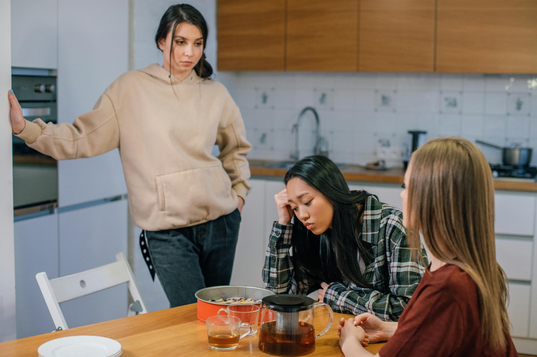Three women in a kitchen offering support during an emotional moment. - dating after long break