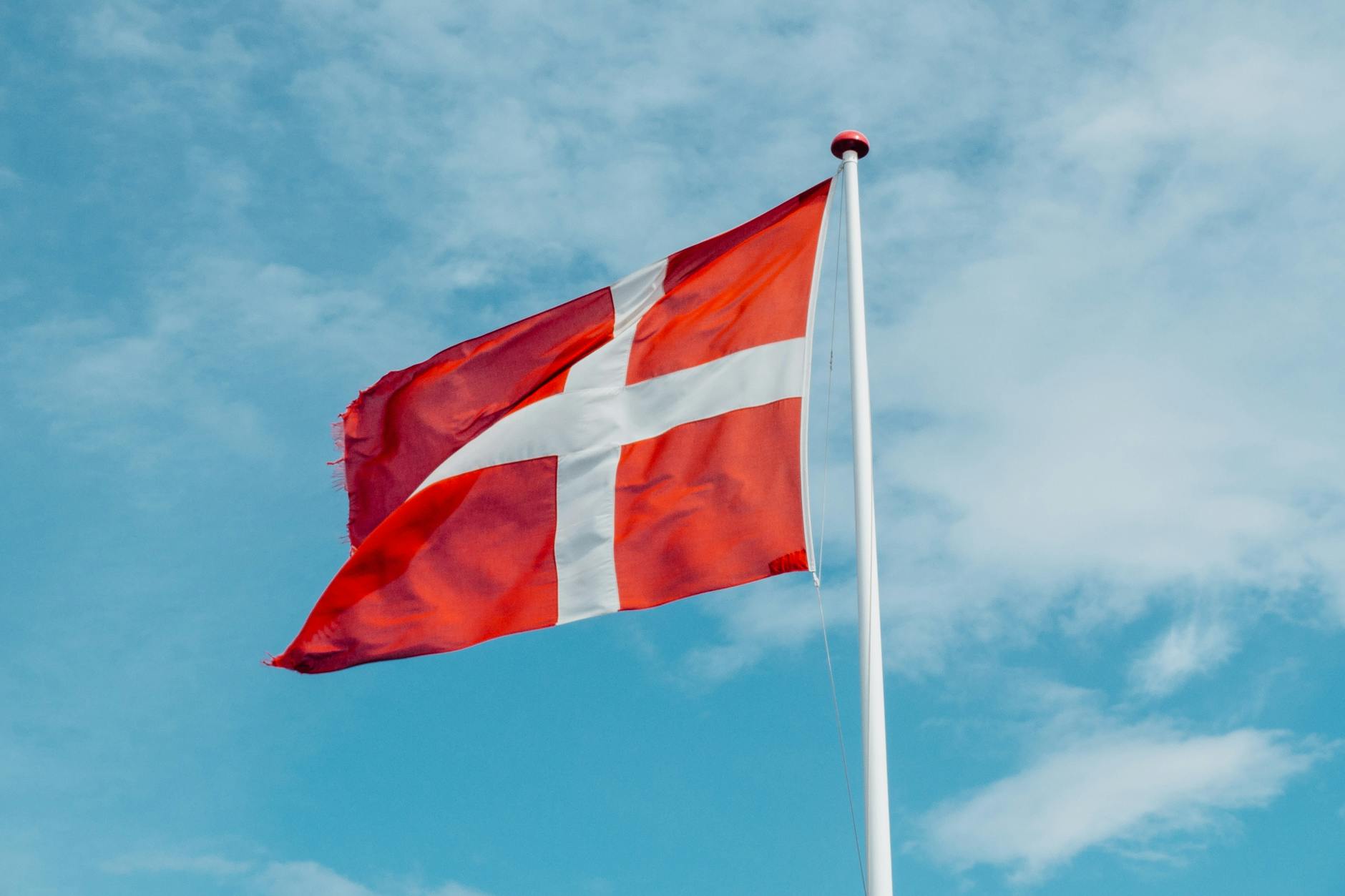 Red and white Danish flag fluttering in the wind, symbolizing national pride on a clear day. - dating red flags