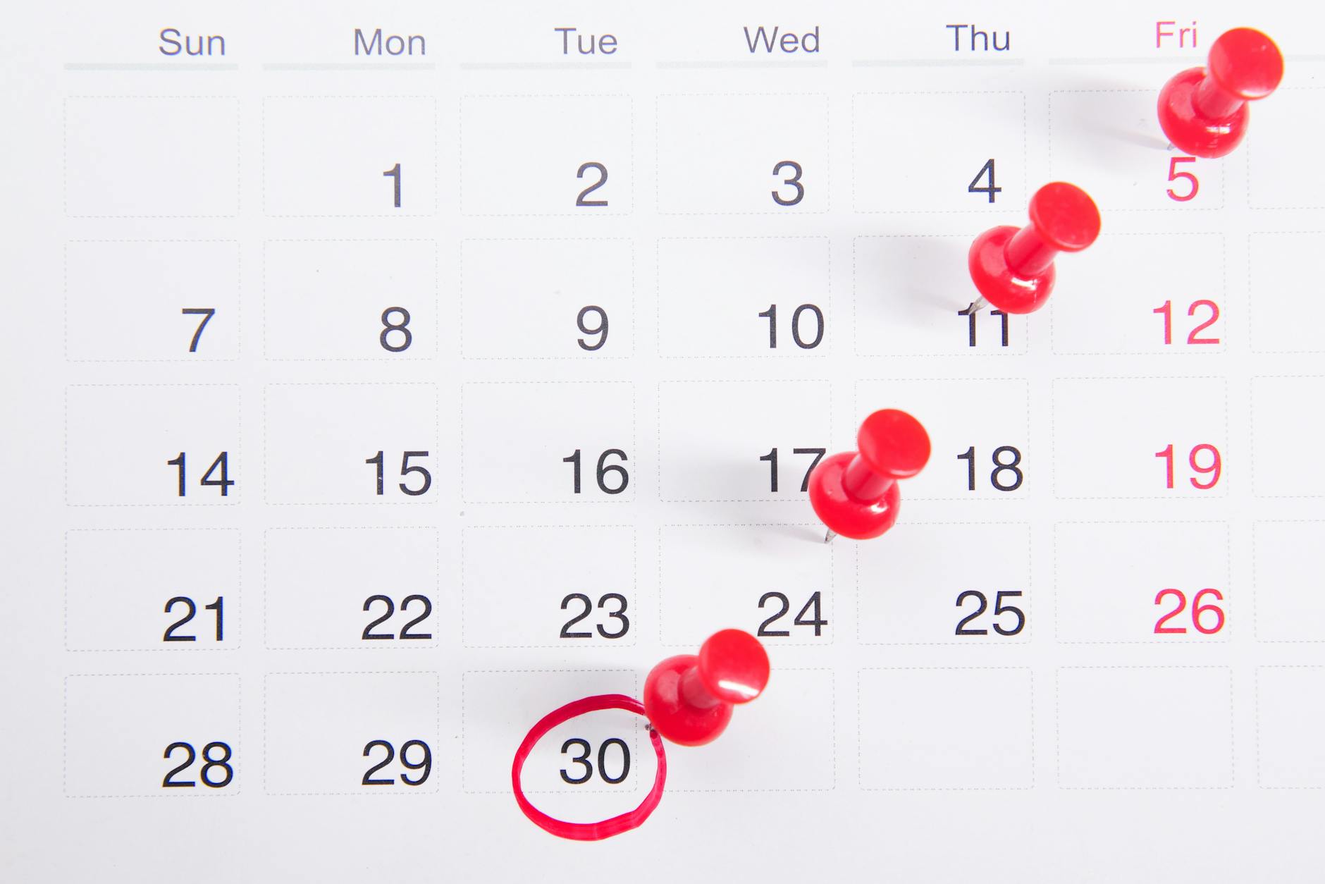 Close-up of a calendar with red push pins marking important dates, emphasizing deadlines. - dating red flags