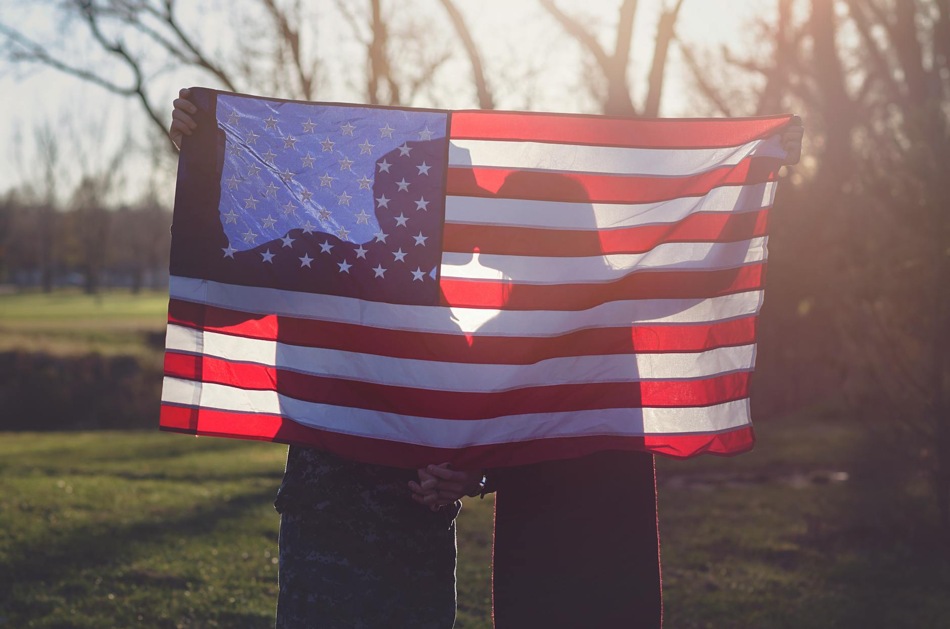 Romantic silhouette of a couple kissing behind an American flag outdoors at sunset. - dating red flags