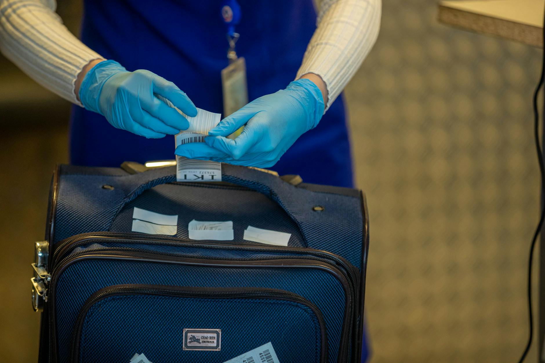 Close-up of airport security process with gloved hands inspecting luggage tags. - declutter emotional baggage