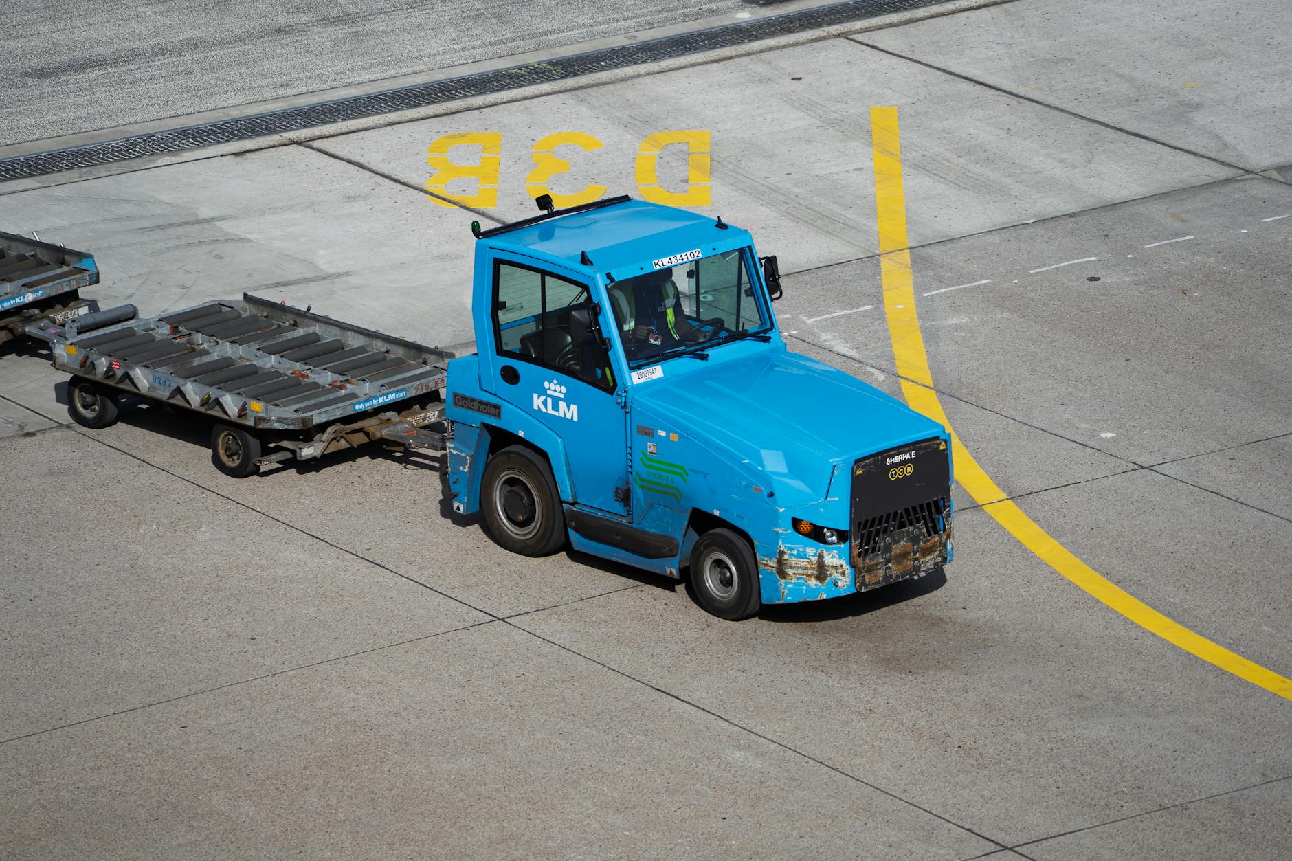 KLM Ground Support Equipment towing baggage carts on airport tarmac. - declutter emotional baggage