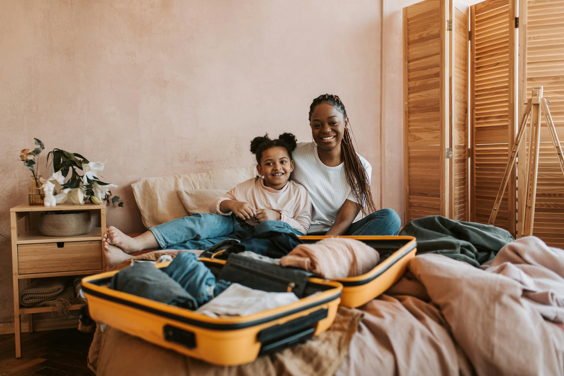Smiling mother and daughter packing luggage together in cozy room. - declutter relationship baggage