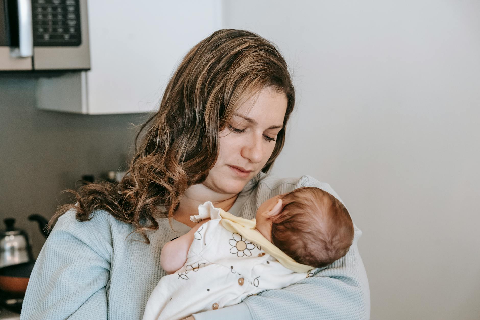A mother tenderly holding her newborn baby, showcasing gentle and loving moments in a home setting. - disorganized attachment