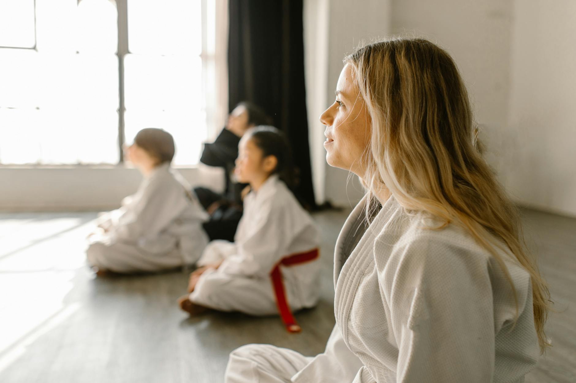 Children and adults attentively listening in a Taekwondo class session indoors. - effective listening skills