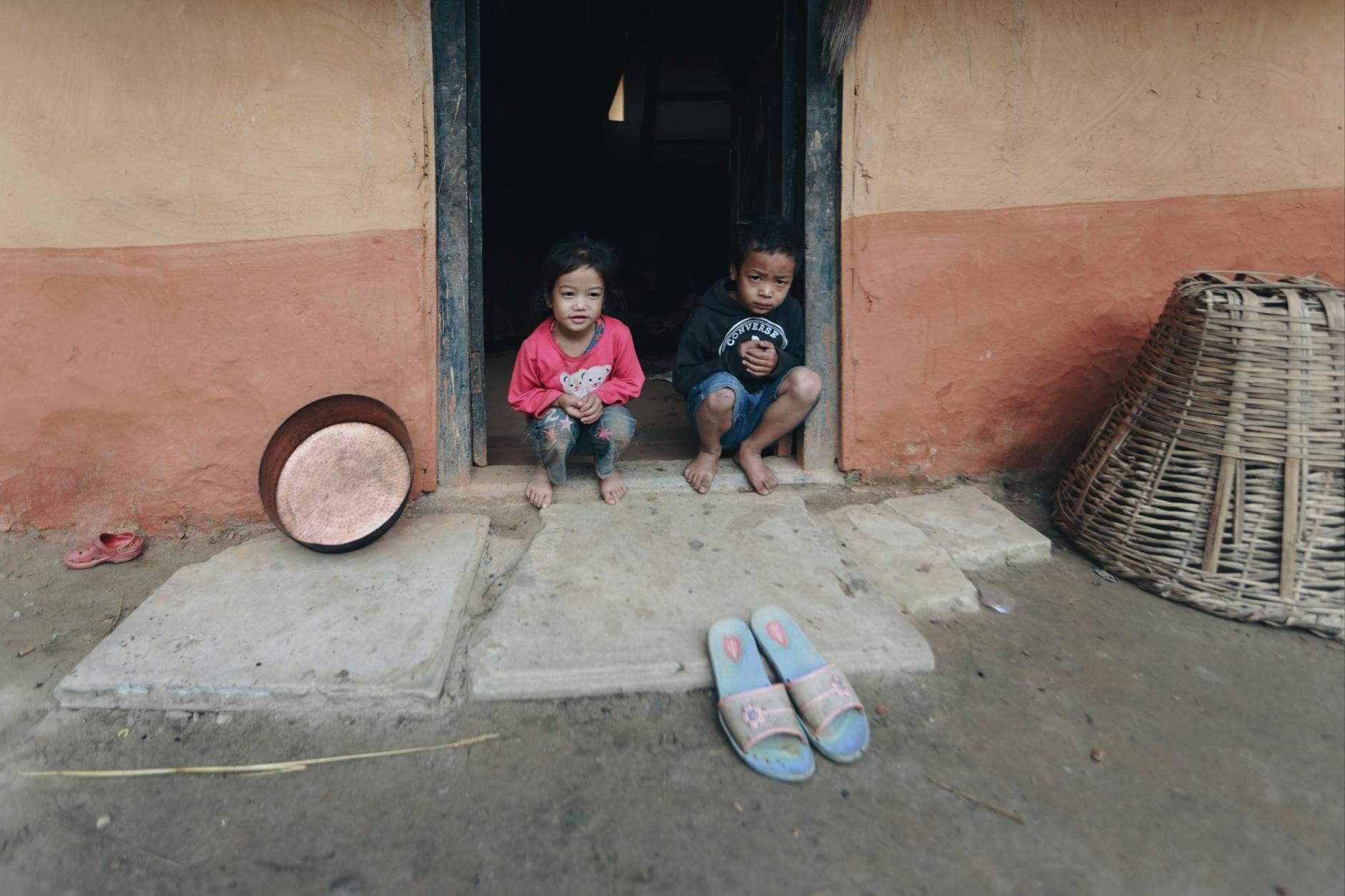 Two children sitting barefoot at the doorstep of their rural house. - emotional resilience children