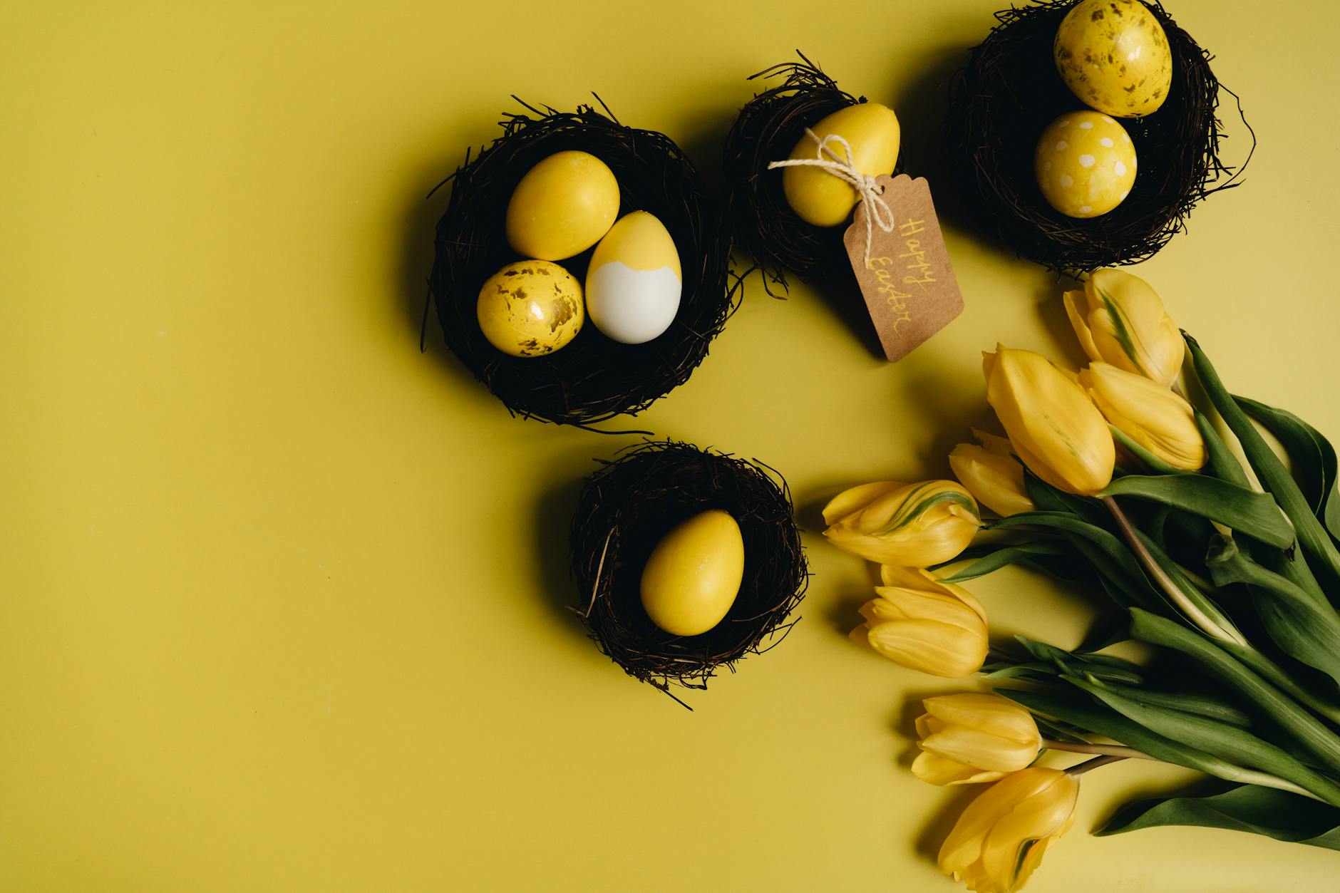 Yellow painted Easter eggs with tulips and nests on a vibrant yellow surface. - empty nest symptoms