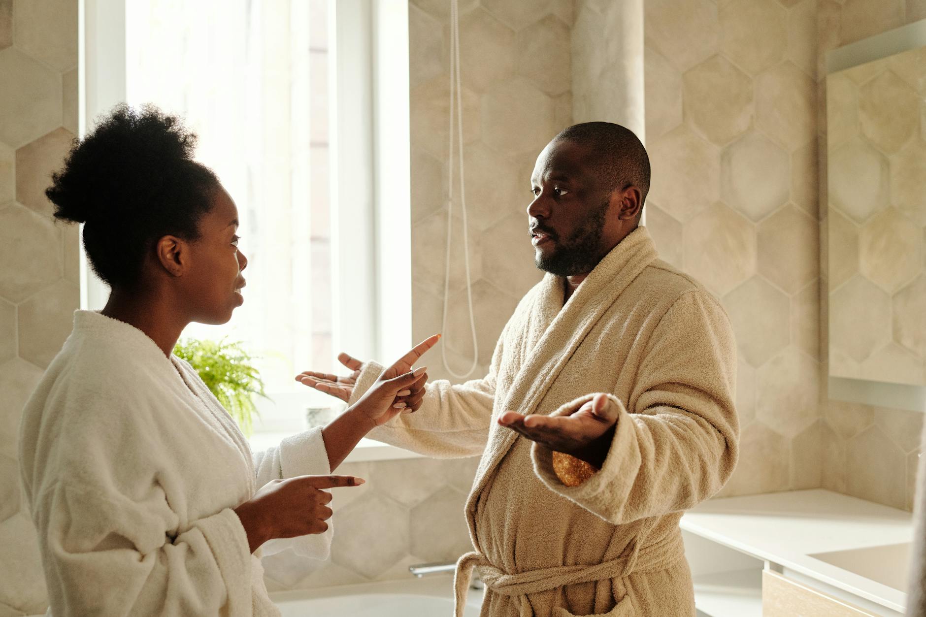 A couple in bathrobes having a discussion in a bathroom setting, expressing emotions. - express needs conflict