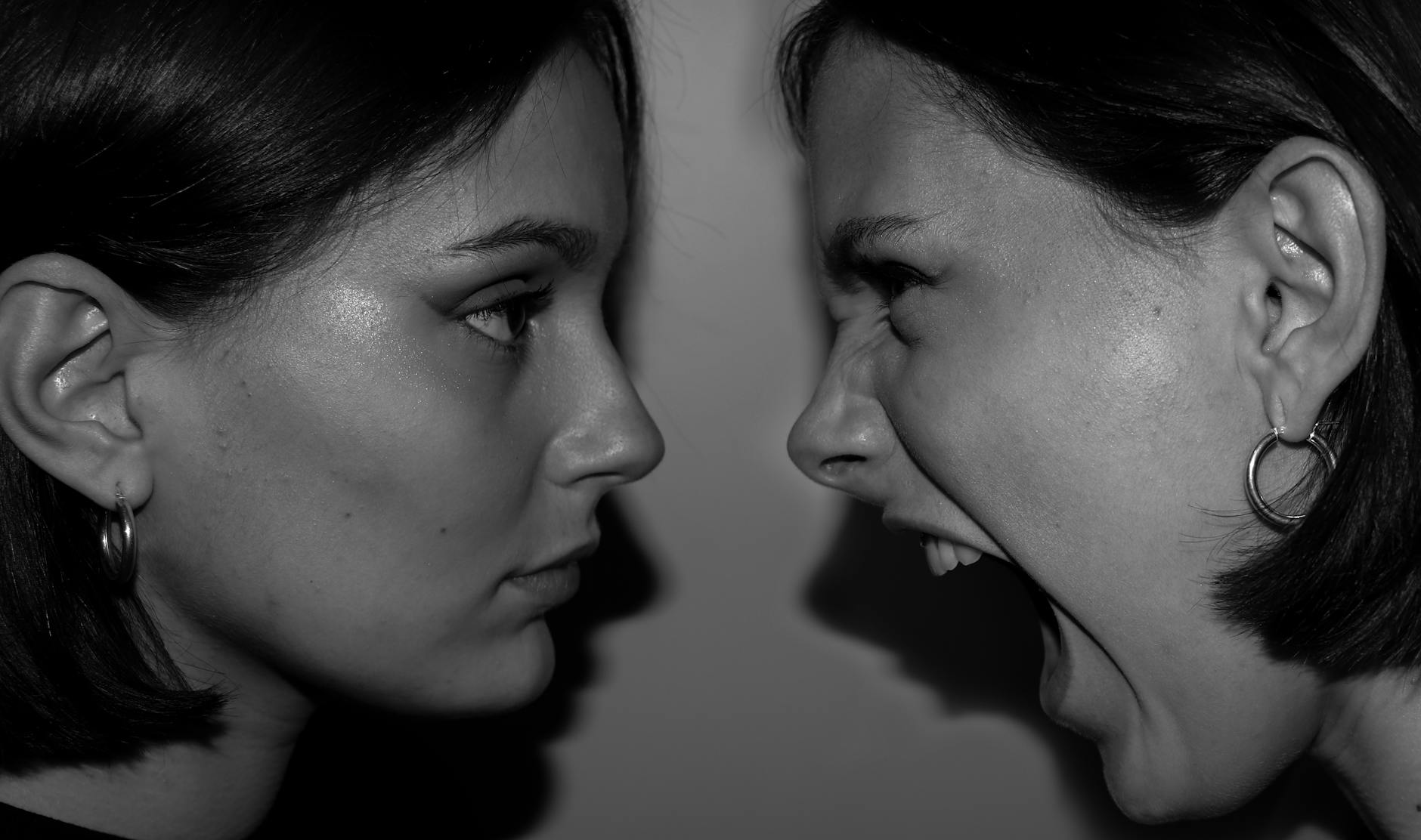 Intense black and white close-up of two women expressing contrasting emotions facing each other. - express needs conflict