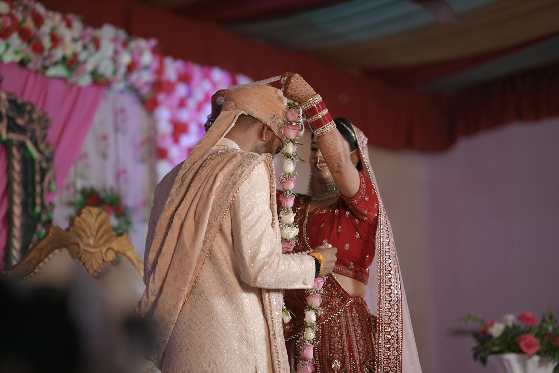 A bride and groom exchange garlands during a traditional Indian wedding ceremony. - express needs marriage