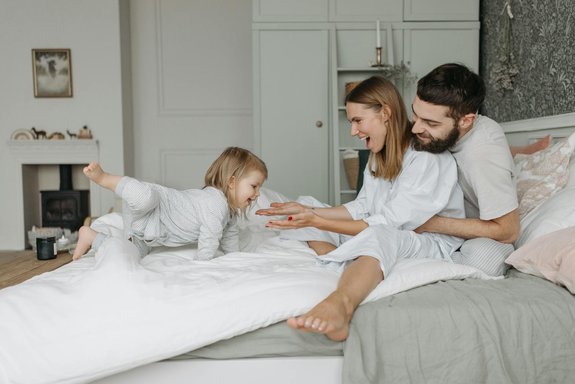 A joyful family morning with parents and child playing on a bed together. - family routines with kids