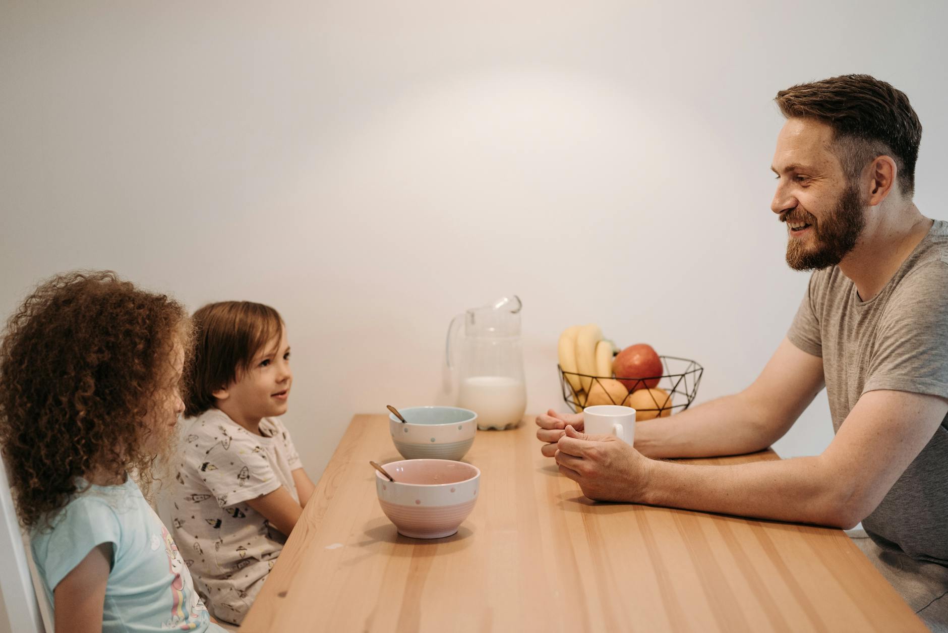 A father having a warm conversation with his children during breakfast at home. - family routines with kids