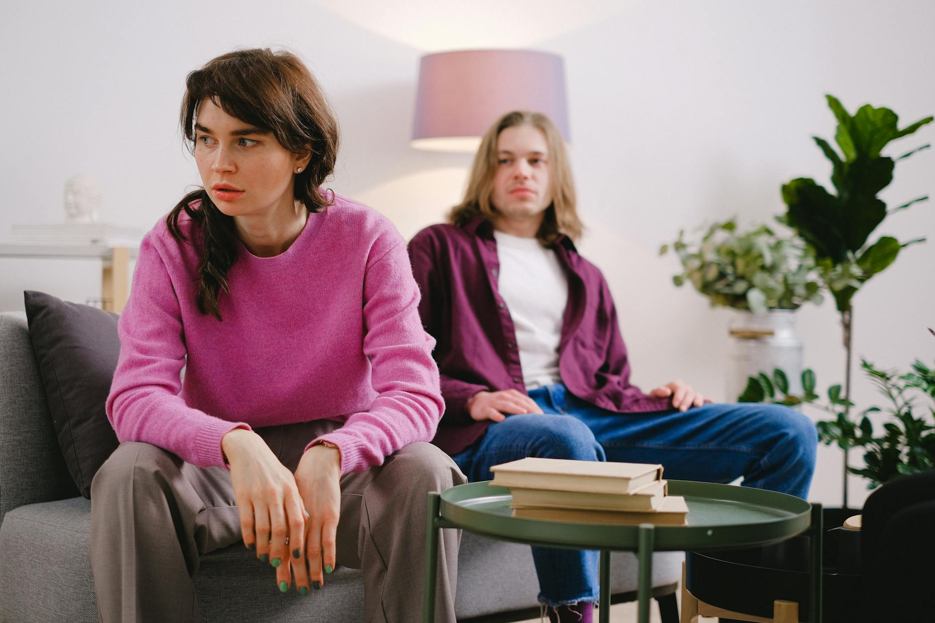 A couple sitting on a sofa with thoughtful expressions, surrounded by home decor. - what is gaslighting