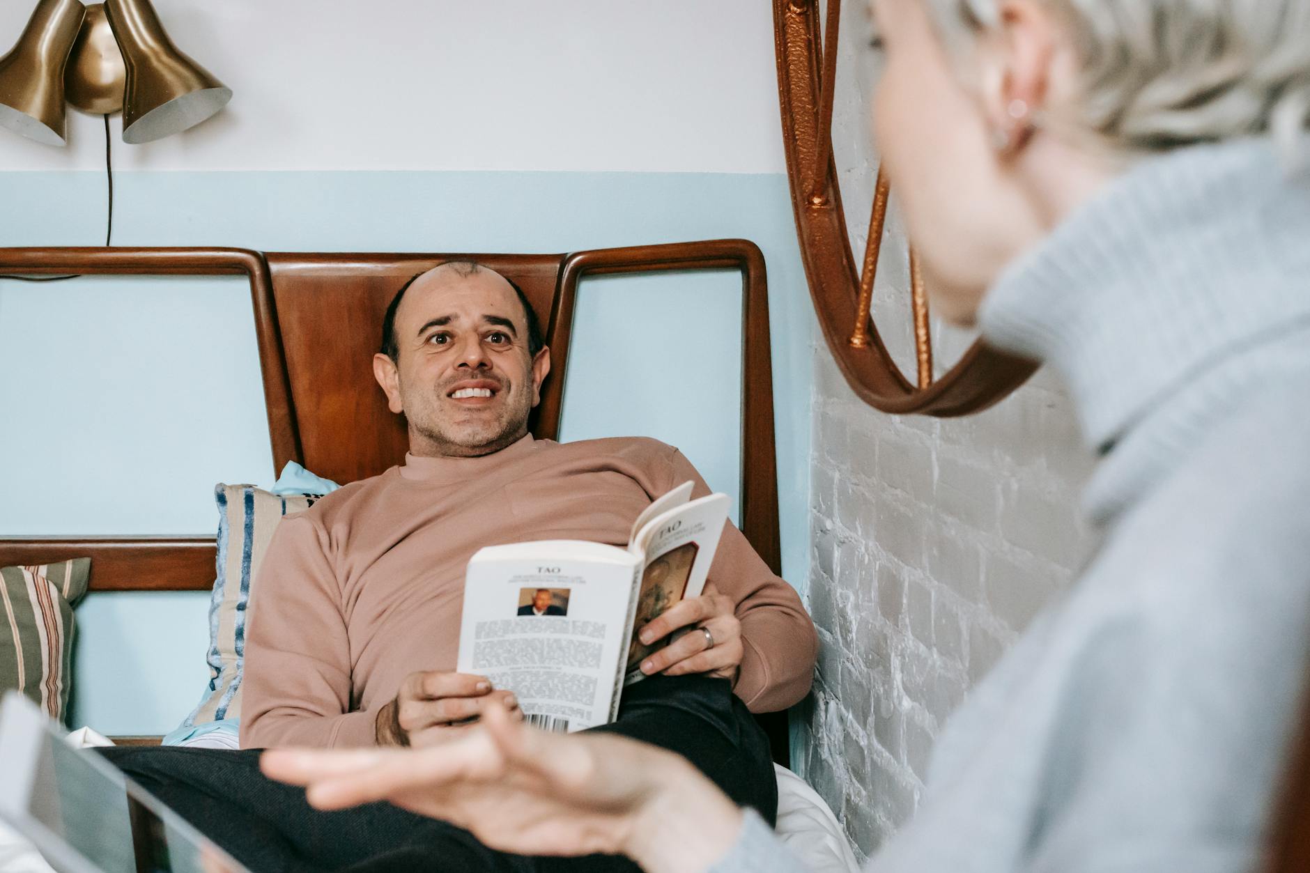Crop unrecognizable woman using tablet while resting on bed near happy adult ethnic husband reading book - what is gaslighting