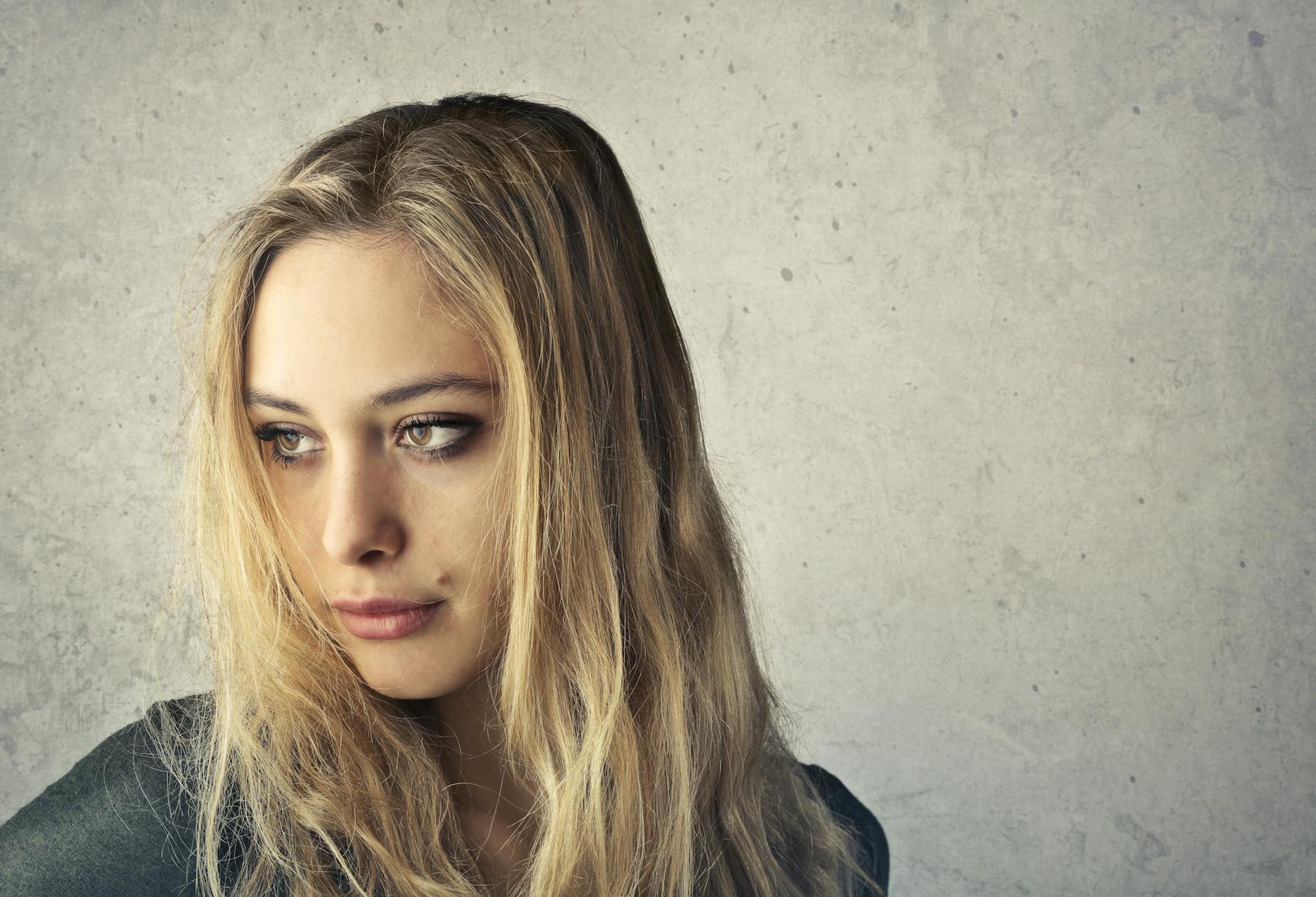 Close-up portrait of a young woman with long blonde hair and striking eye makeup. - gaslighting examples