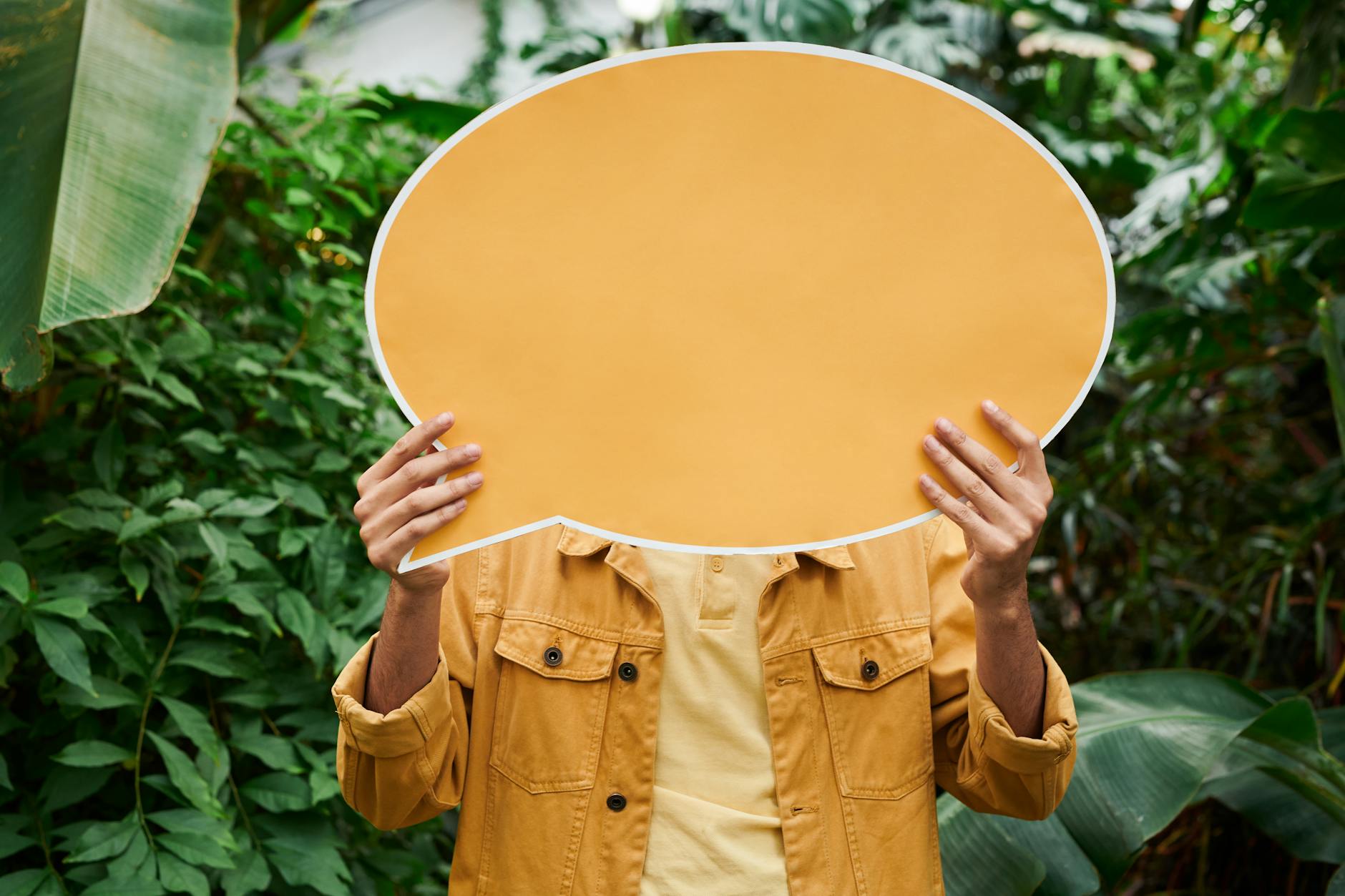 Person holding a blank yellow sign in a vibrant garden. Ideal for creativity and messaging concepts. - gaslighting signs