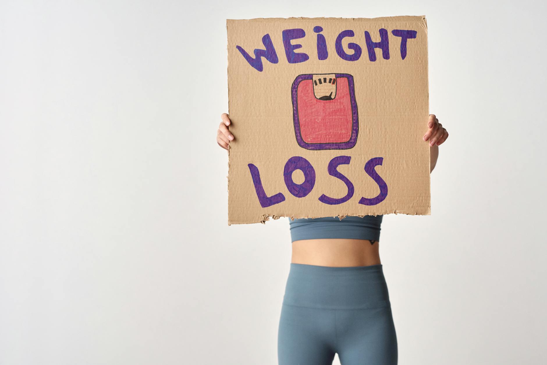 Person holding 'weight loss' sign for fitness motivation and health goals. - healthy relationship signs