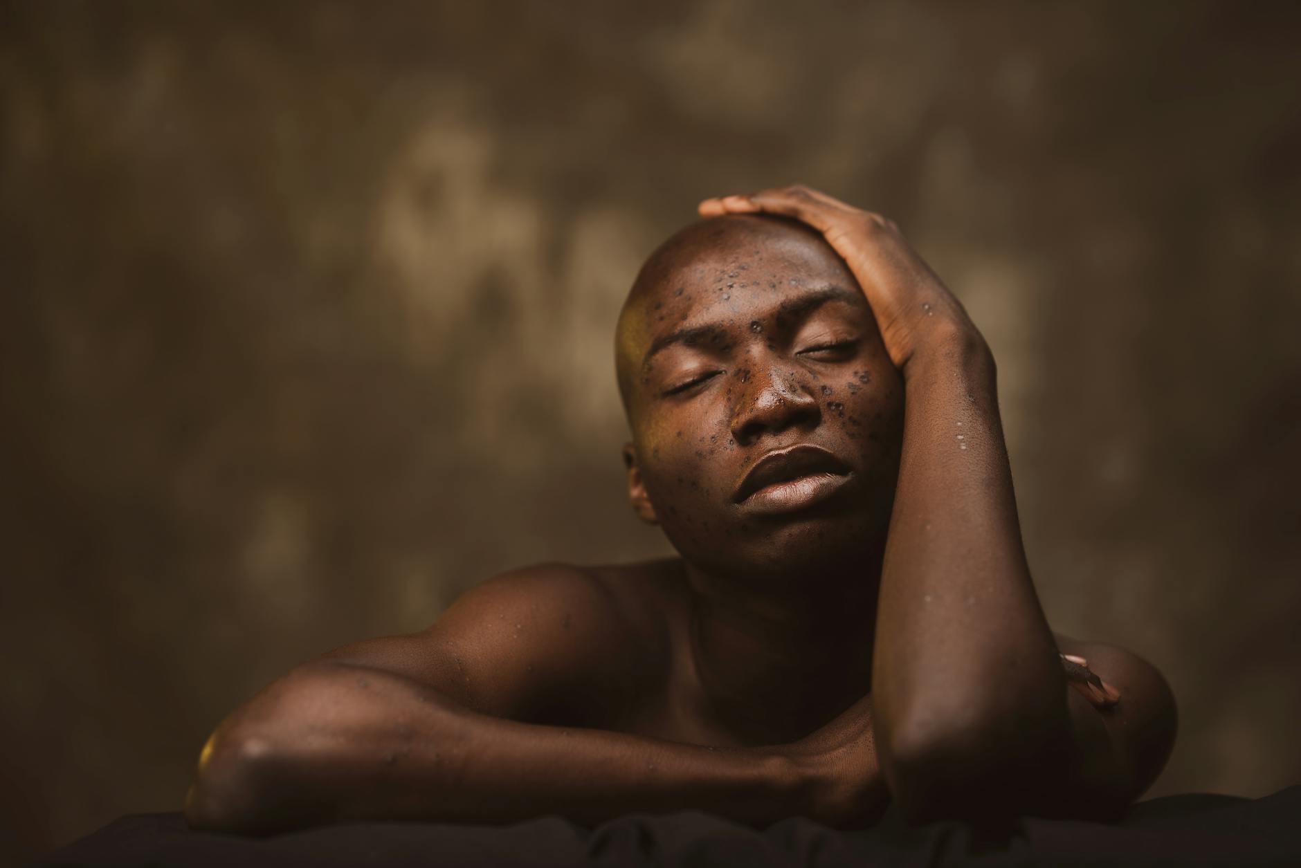 A serene studio portrait of a shirtless black man with freckles and closed eyes. - journaling emotional release