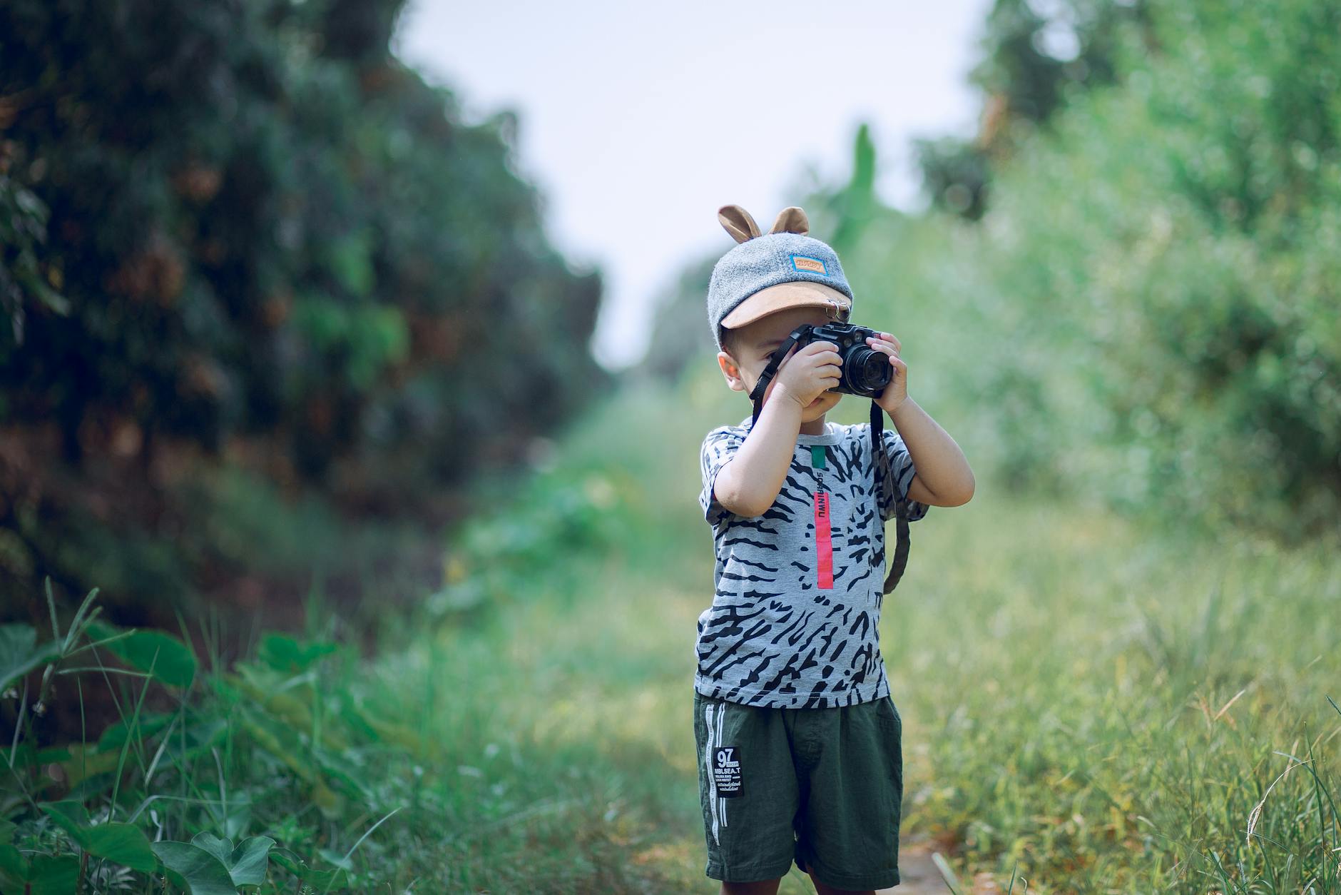 A young child engages in creative photography outdoors, capturing nature’s beauty with a camera. - kids nature exploration