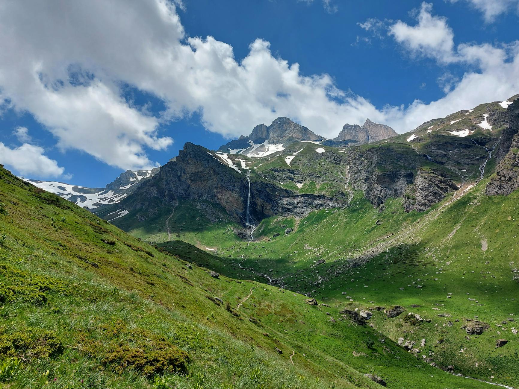 Beautiful summer scene of Radomirë mountains with lush greenery, snow patches, and a waterfall. - lack of empathy