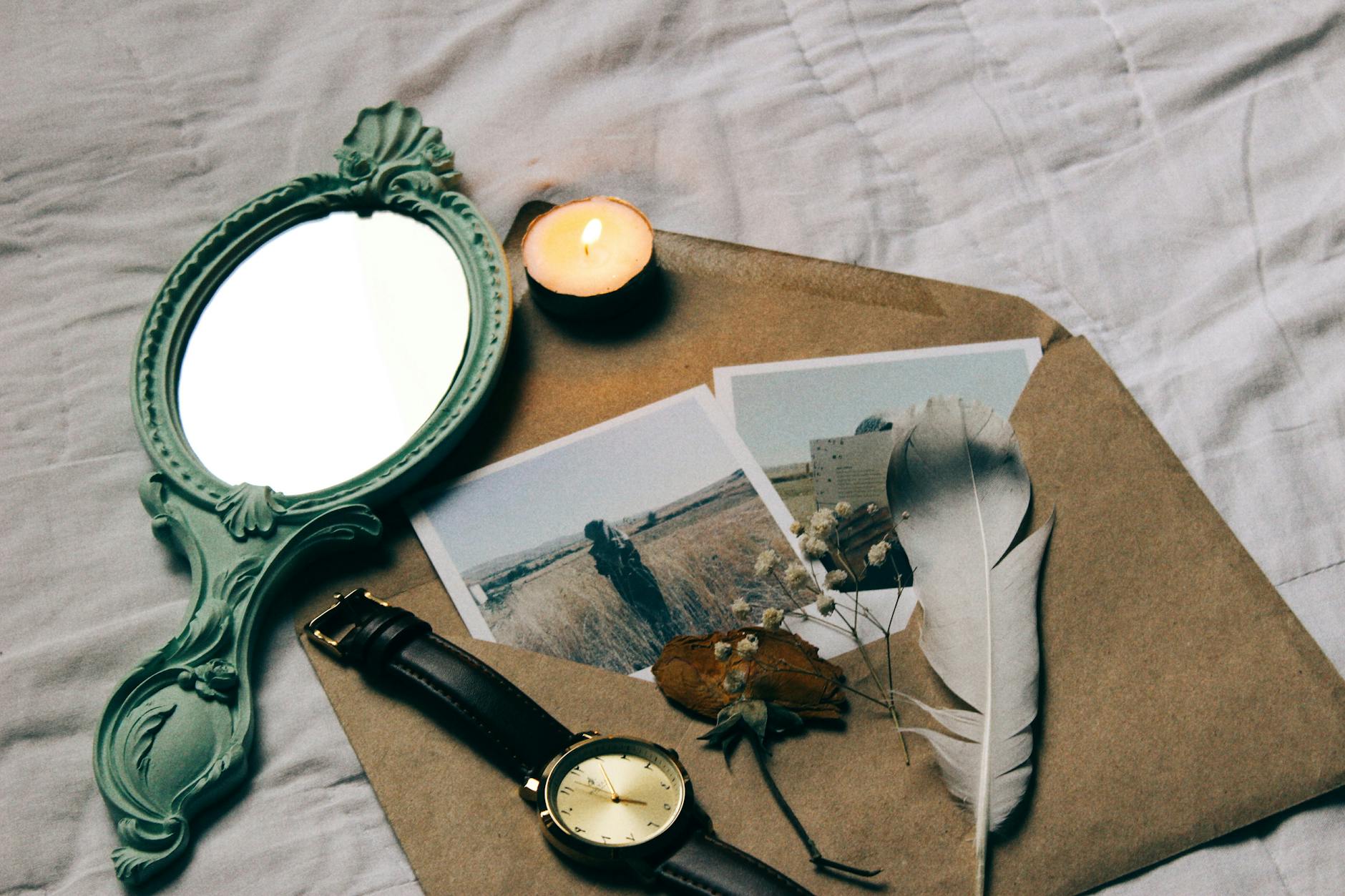 Aesthetic composition with vintage mirror, photos, candle, and feather. - let go of past hurts