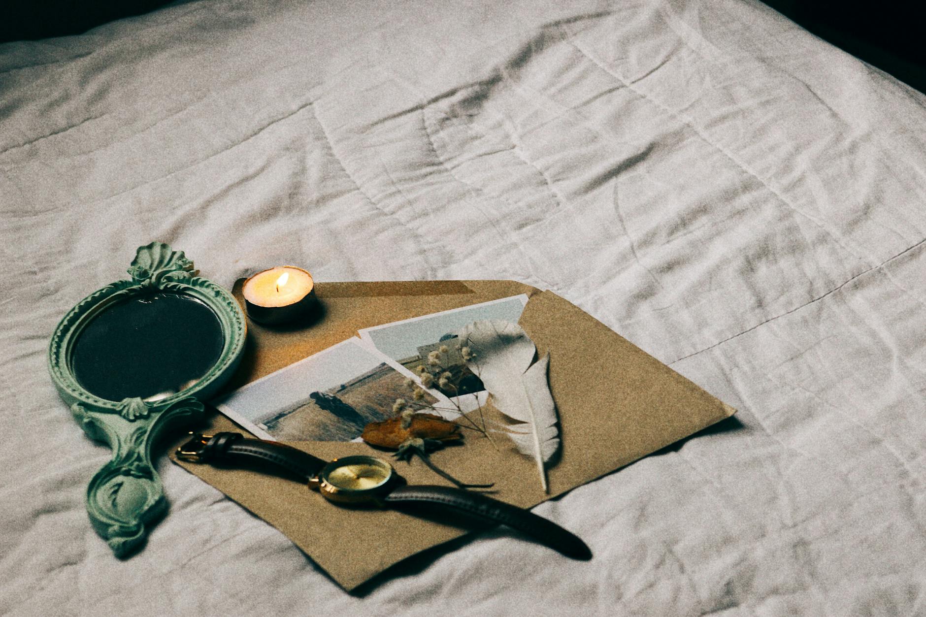 Flat lay of vintage items including a mirror, envelope, and watch on a bed. - let go of past hurts