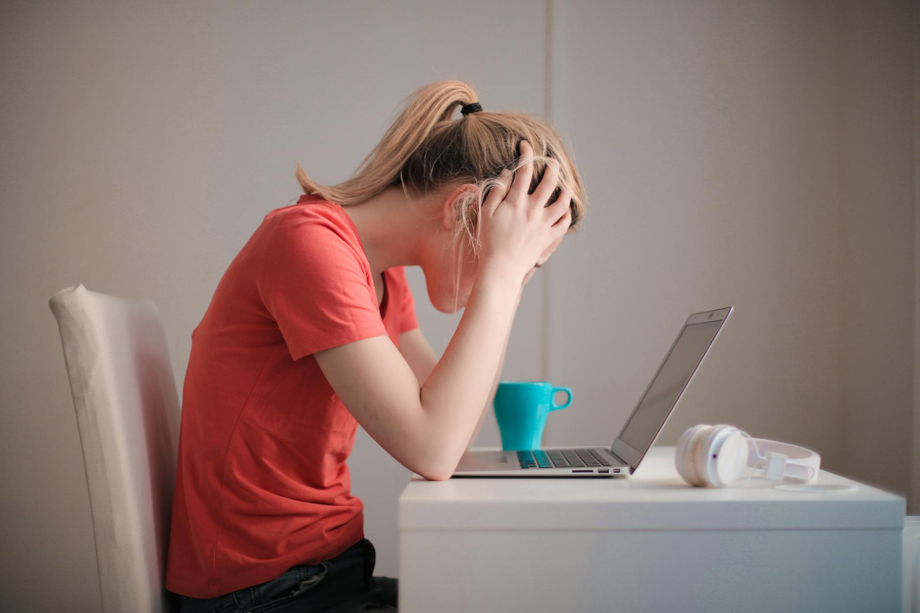 Young woman feeling stressed while studying at home with a laptop and coffee cup. - manage overwhelm cbt