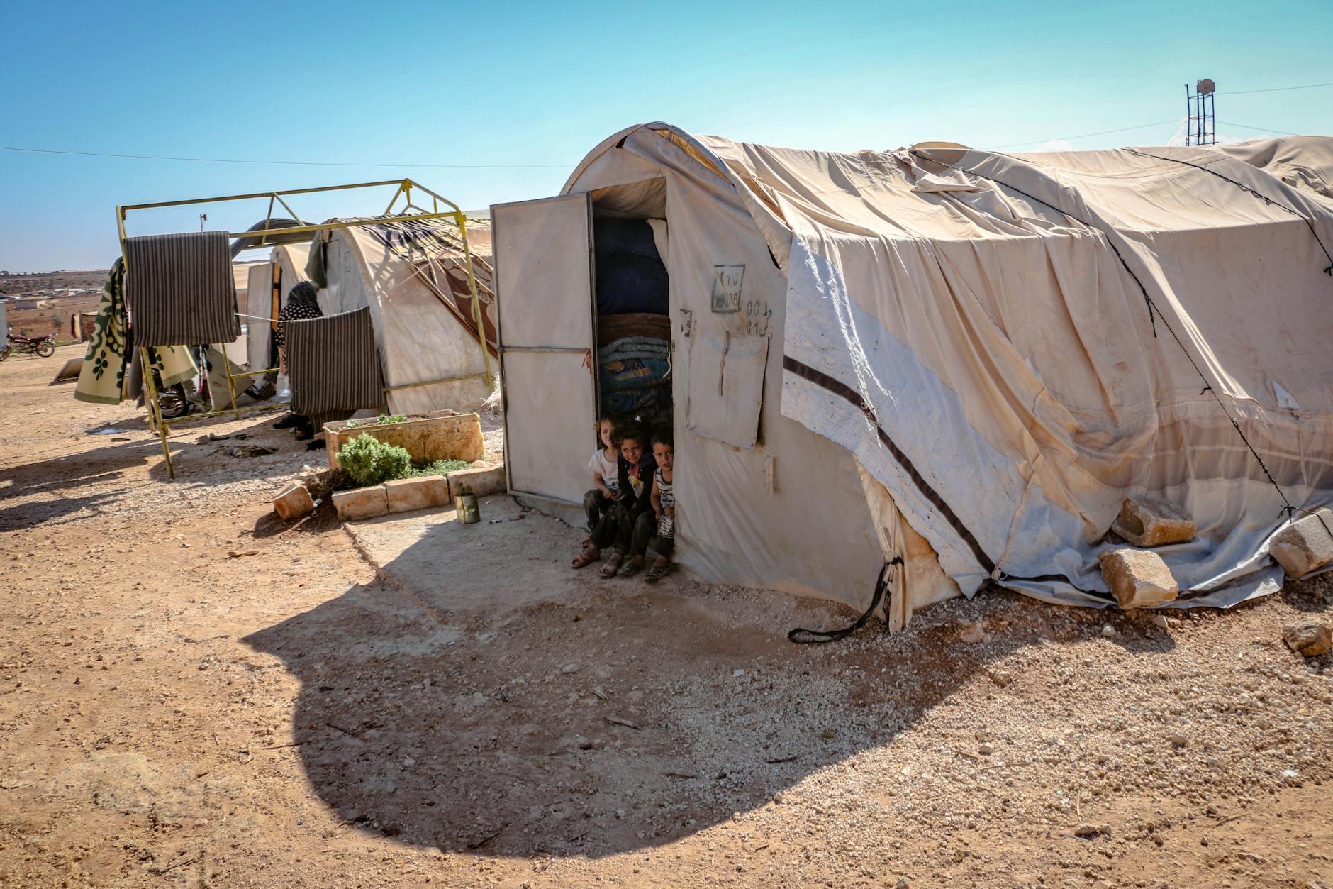 Young children standing near tents in a refugee camp in Idlib, Syria. Focus on poverty and displacement. - managing family conflict spring holidays