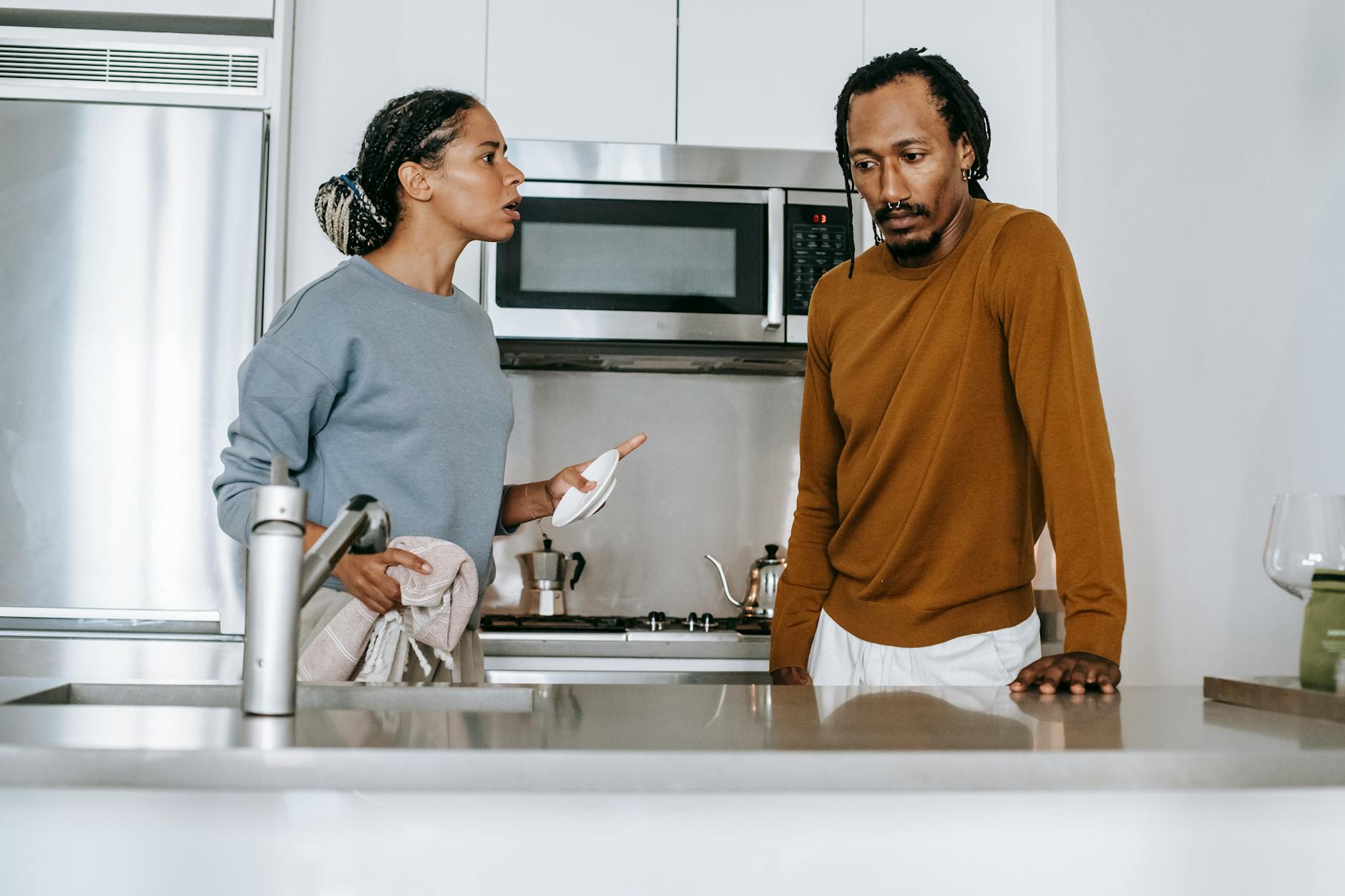 An african american couple engaged in a serious dialogue in their modern kitchen. - marital resentment