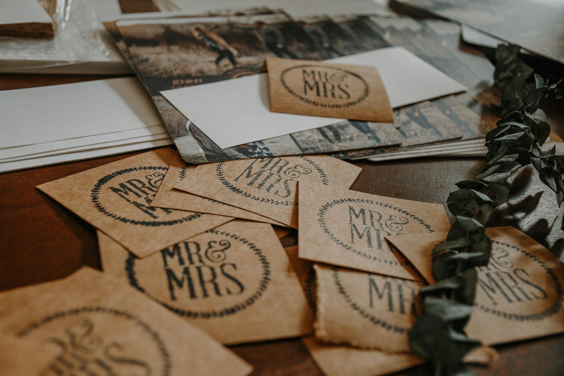 A collection of rustic wedding invitation cards with 'Mr & Mrs' text on a wooden table. - marriage advice cards