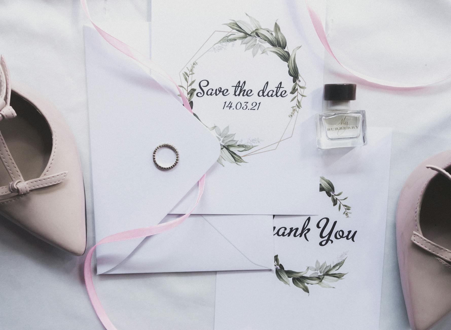 Stylish flat lay of wedding invitations, ring, perfume, and shoes for a chic celebration. - marriage advice cards
